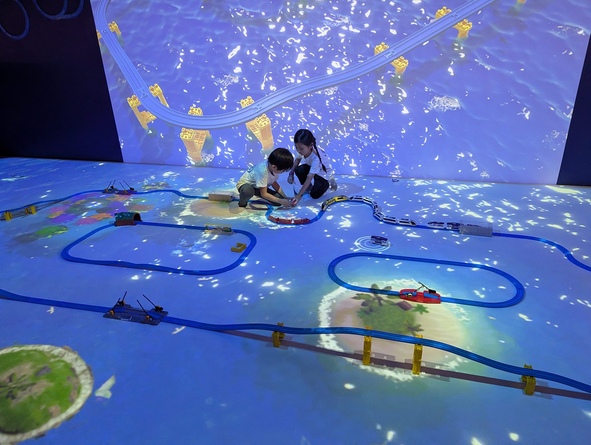 「プラレールファンタジーワールド」エリアはレールを敷設して自由に車両を走らせて遊べるアトラクション。壁面には大画面で現在の背景映像が投射されているほか、床にも同様の背景映像が投射されている