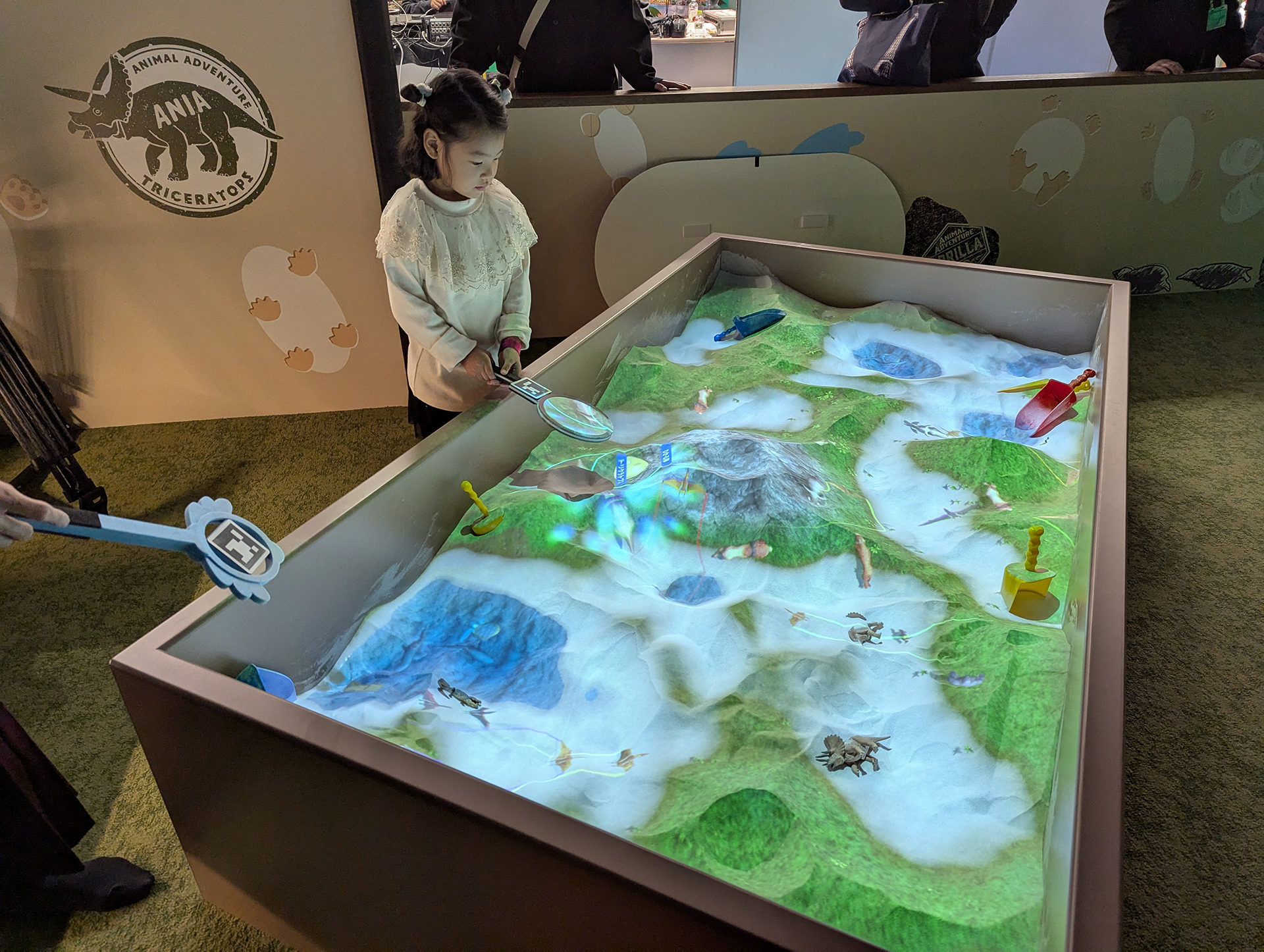 近未来の砂場といったテイストを感じさせる「トミカ＆アニア サンドアドベンチャー」。砂を弄ることで表示される地形が変化したり、動物や昆虫などが発見できる。砂自体は粘性がなく、非常にサラサラしており、手に付くことなどはほとんどなかったが、やはりほこりなどの微粒子は舞うようで、天井に設置するプロジェクションマッピングの機材メンテが大変そうだ