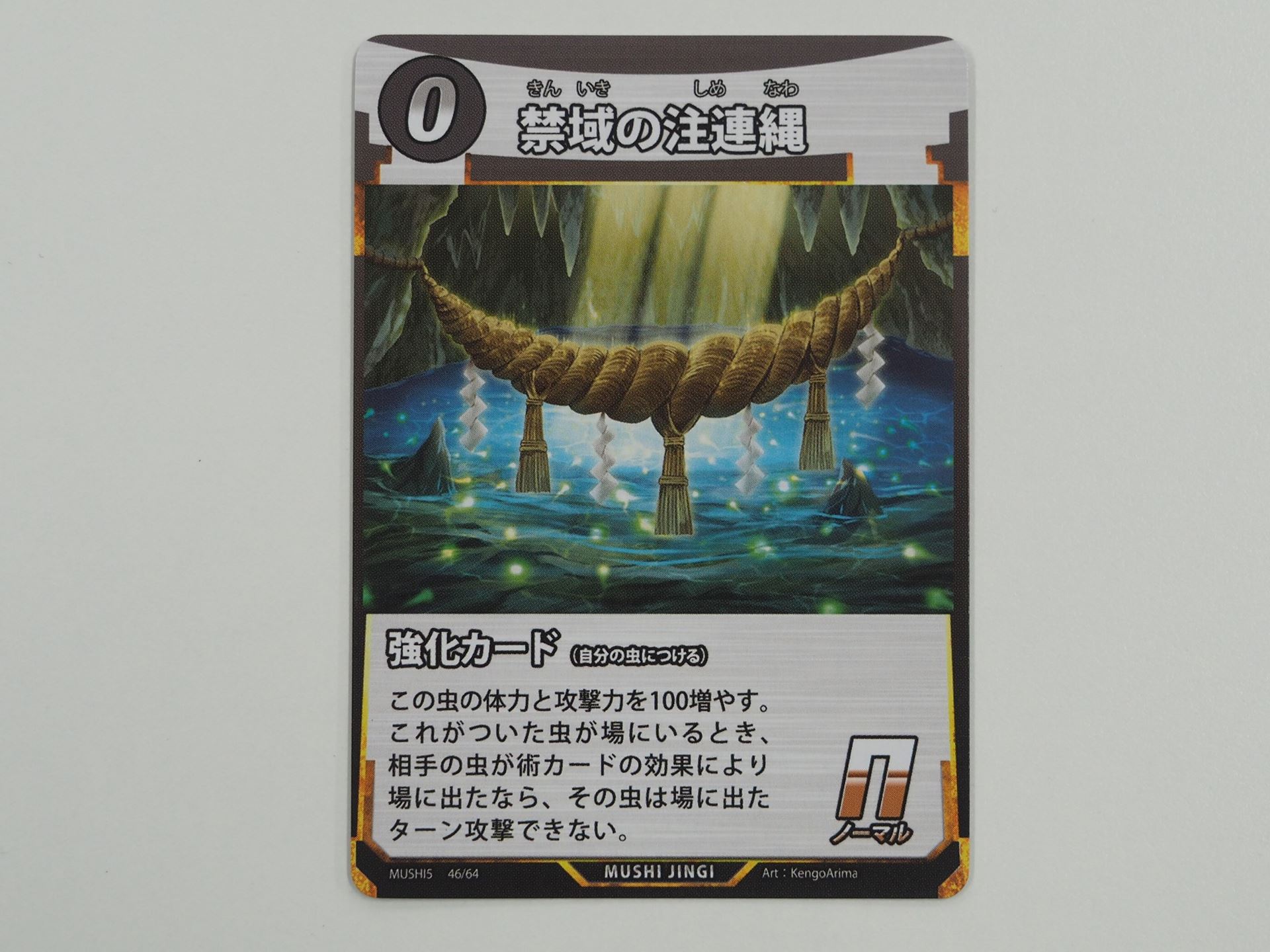 0コストのN強化カード「禁域の注連縄」。先行体験会で初出のカード。付けた虫の体力と攻撃力を100ずつ増やし、相手の虫が術カードの効果で場に出た場合、その虫は場に出たターンに攻撃できなくする能力を持つ