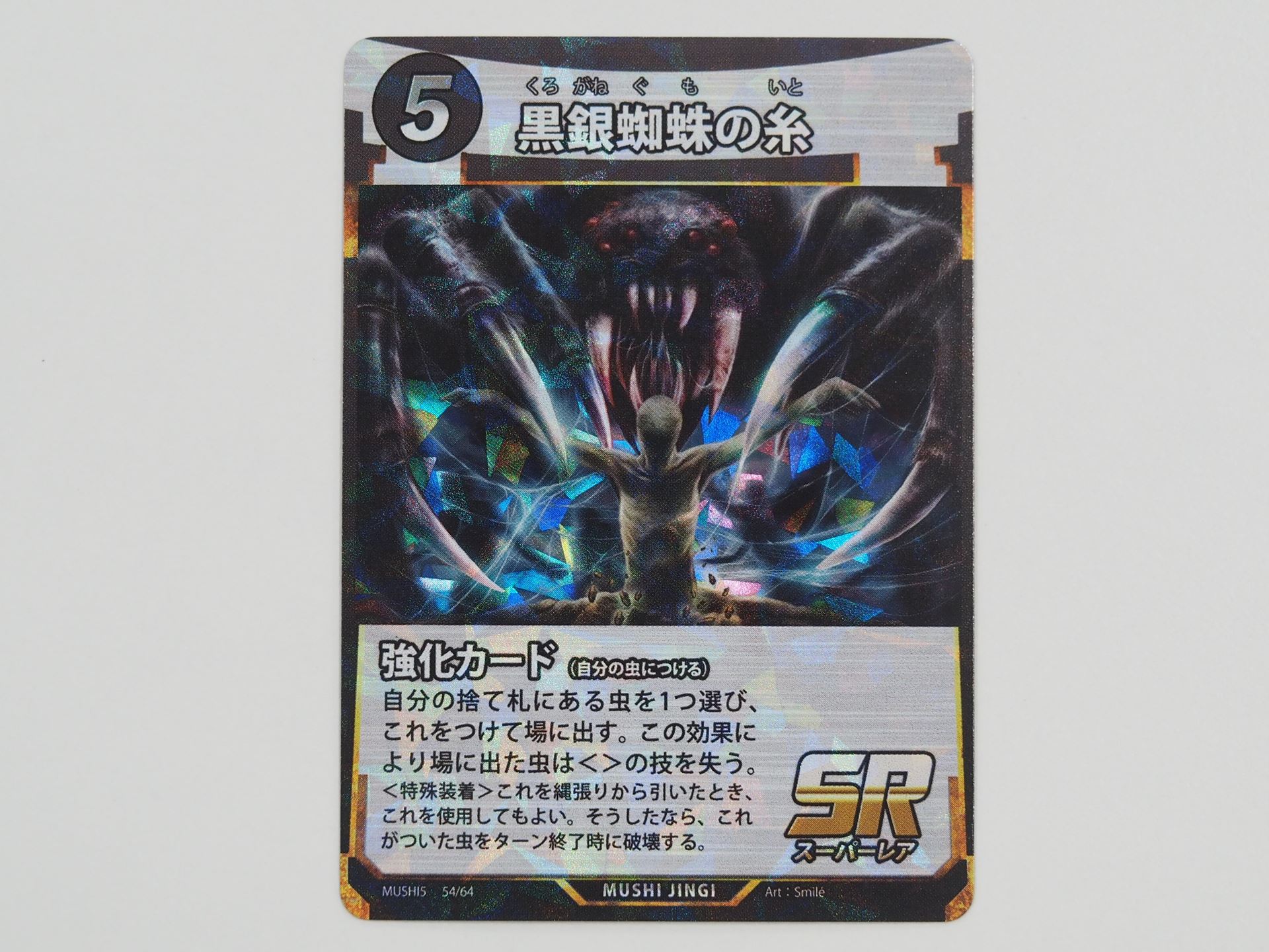 5コストのSR強化カード「黒銀蜘蛛の糸」。捨て札にある虫1つを選んで、付けて場に出すことができる。この効果によって場に出た虫は＜＞の技を失うので、レギウスオオツノハナムグリを出すのに適している