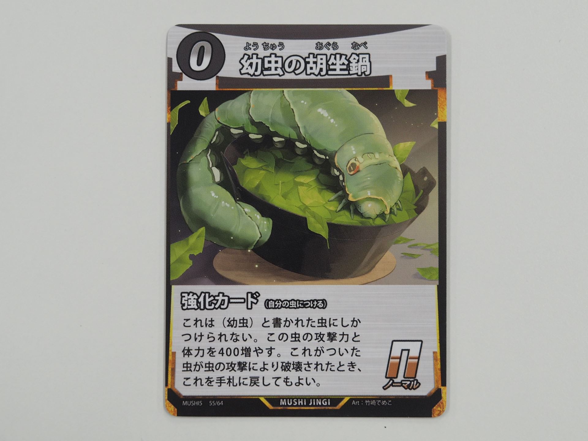 0コストのN強化カード「幼虫の胡坐鍋」。先行体験会で初出のカード。幼虫専用の強化カードであり、これが付いた虫が虫の攻撃によって破壊されたとき、手札に戻すことができる