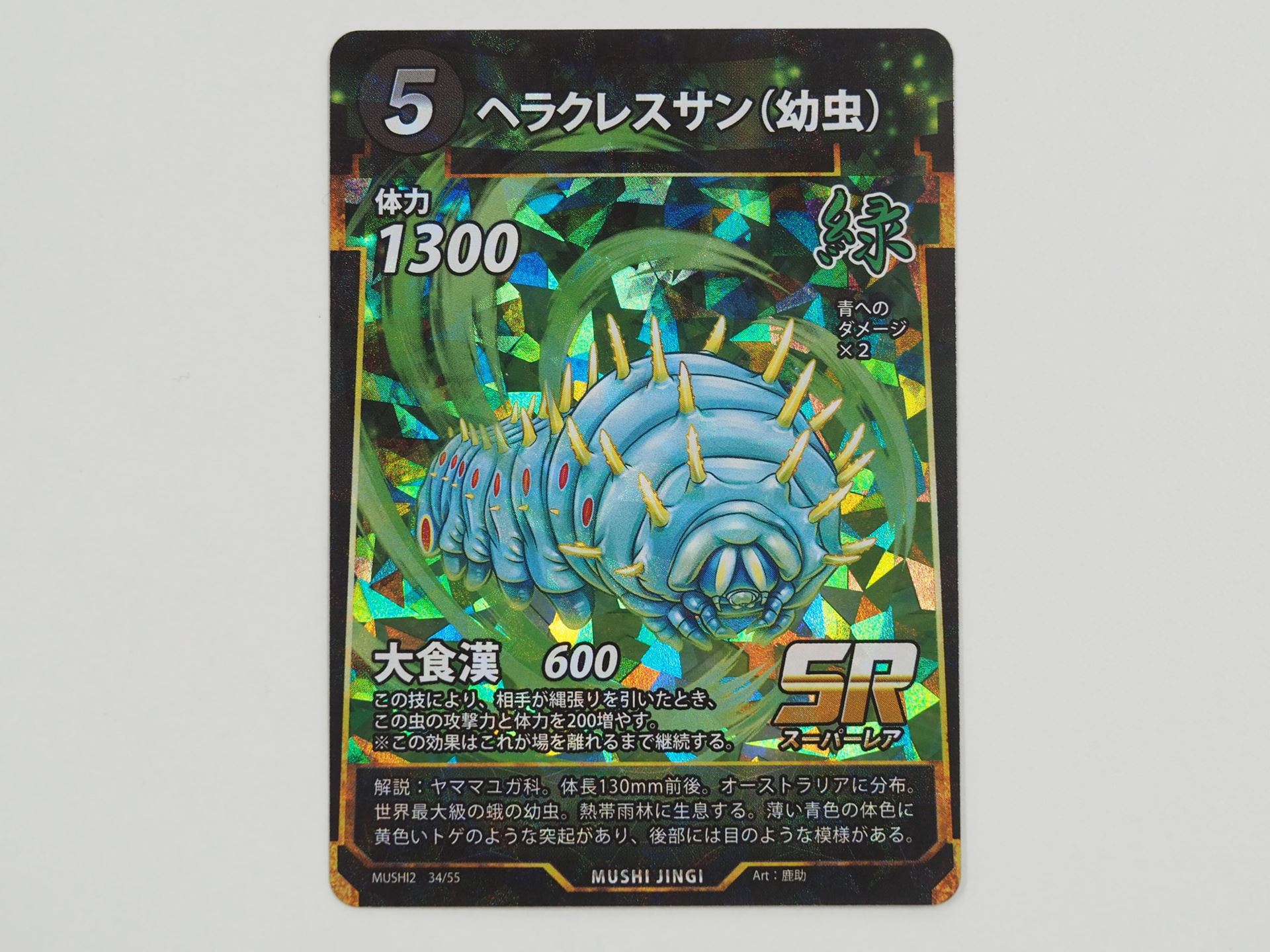 緑5コストのSRカード「ヘラクレスサン（幼虫）」。この虫の攻撃で相手が縄張りを引いたとき、攻撃力と体力を200増やす「大食漢」という技を持つ