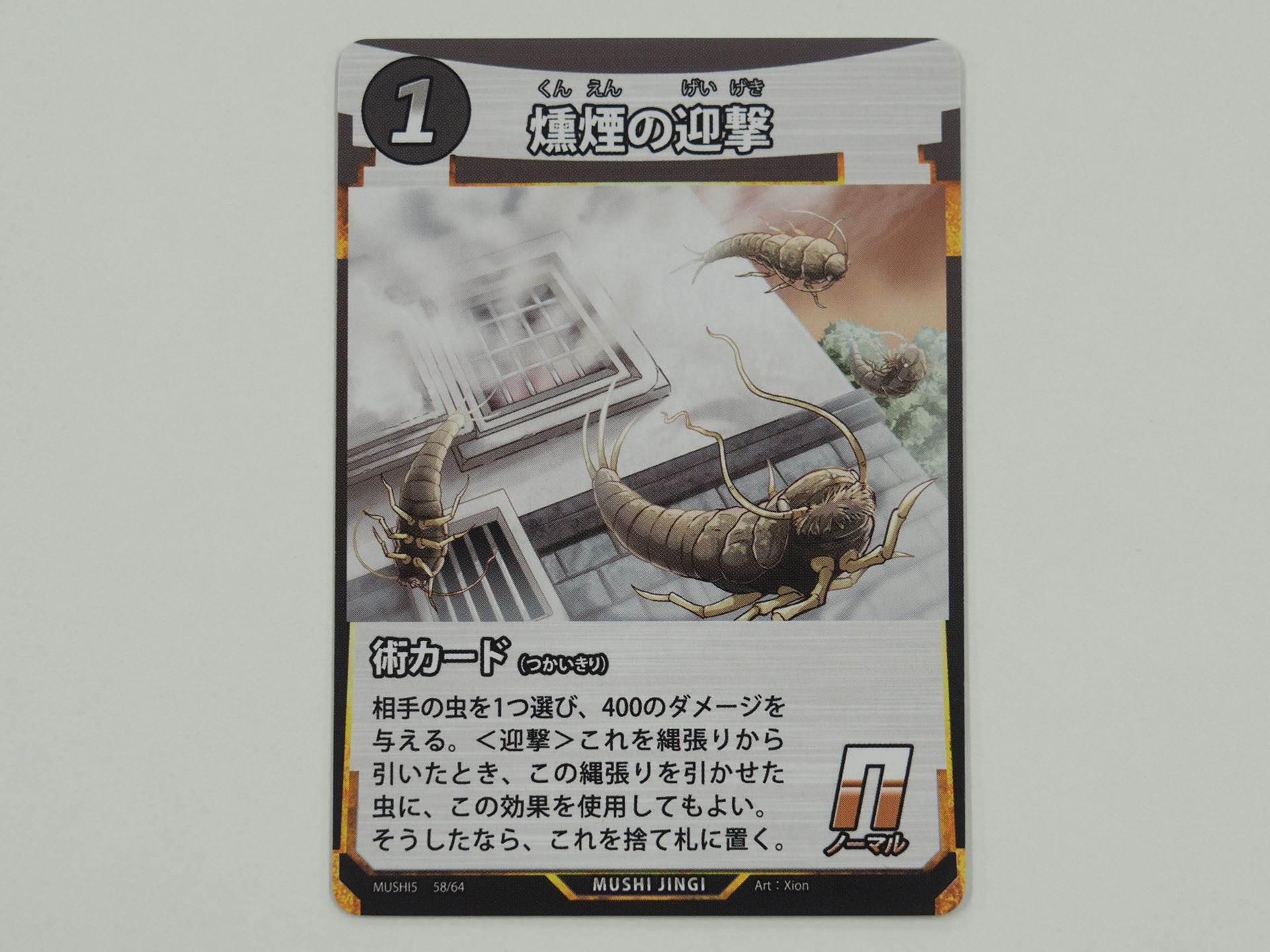 1コストのN術カード「燻煙の迎撃」。先行体験会で初出のカード。相手の虫1体に400ダメージを与える。縄張りから引いたときに、この縄張りを引かせた虫に適用できる＜迎撃＞を持つ