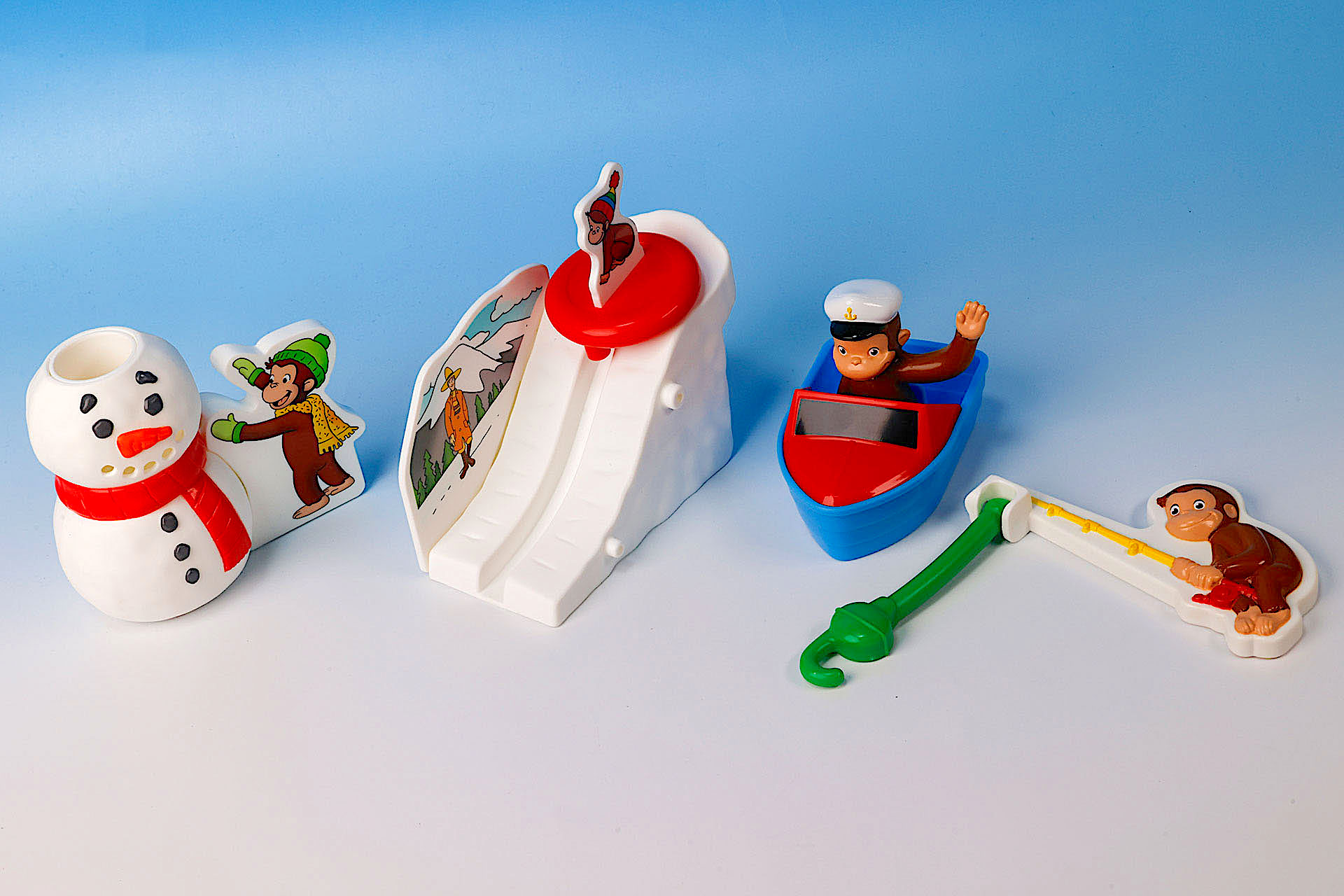 こちらが第2弾（12月27日〜2025年1月9日）のハッピーセット「おさるのジョージ」に登場するおもちゃ。写真左から「ジョージとゆきだるまジョーロ」、「ジョージのゆきやまスライダー」、「ふなのりジョージ」、「ジョージのつりあそび」