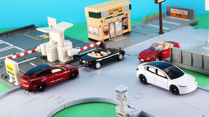 「No.98 テスラ モデル 3」初回特別仕様（左：レッド）・通常仕様（右：ホワイト）、「トミカプレミアム 14 マツダ ユーノス ロードスター」通常仕様（中央左：ブラック）・発売記念仕様（中央右：レッド）