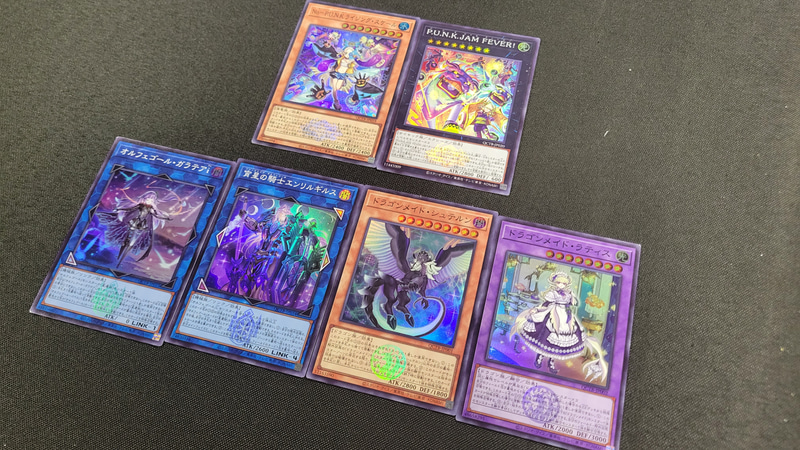 コチラが最終的な1ボックスの開封結果。新規収録のカードは全て1枚ずつ揃うためプレーヤーとしては嬉しい所だ。このボックスでは新規カードの「P.U.N.K.JAM FEVER！」のクォーターセンチュリーシークレットレアを当てたが、追加で購入した「オルフェゴール」のボックスからは再録枠の「星杯の神子イヴ」のクォーターセンチュリーシークレットレアが出た。今回の3テーマは最高レアリティのカードの種類が多いことでデッキ内をキラキラにしやすくなったと言える