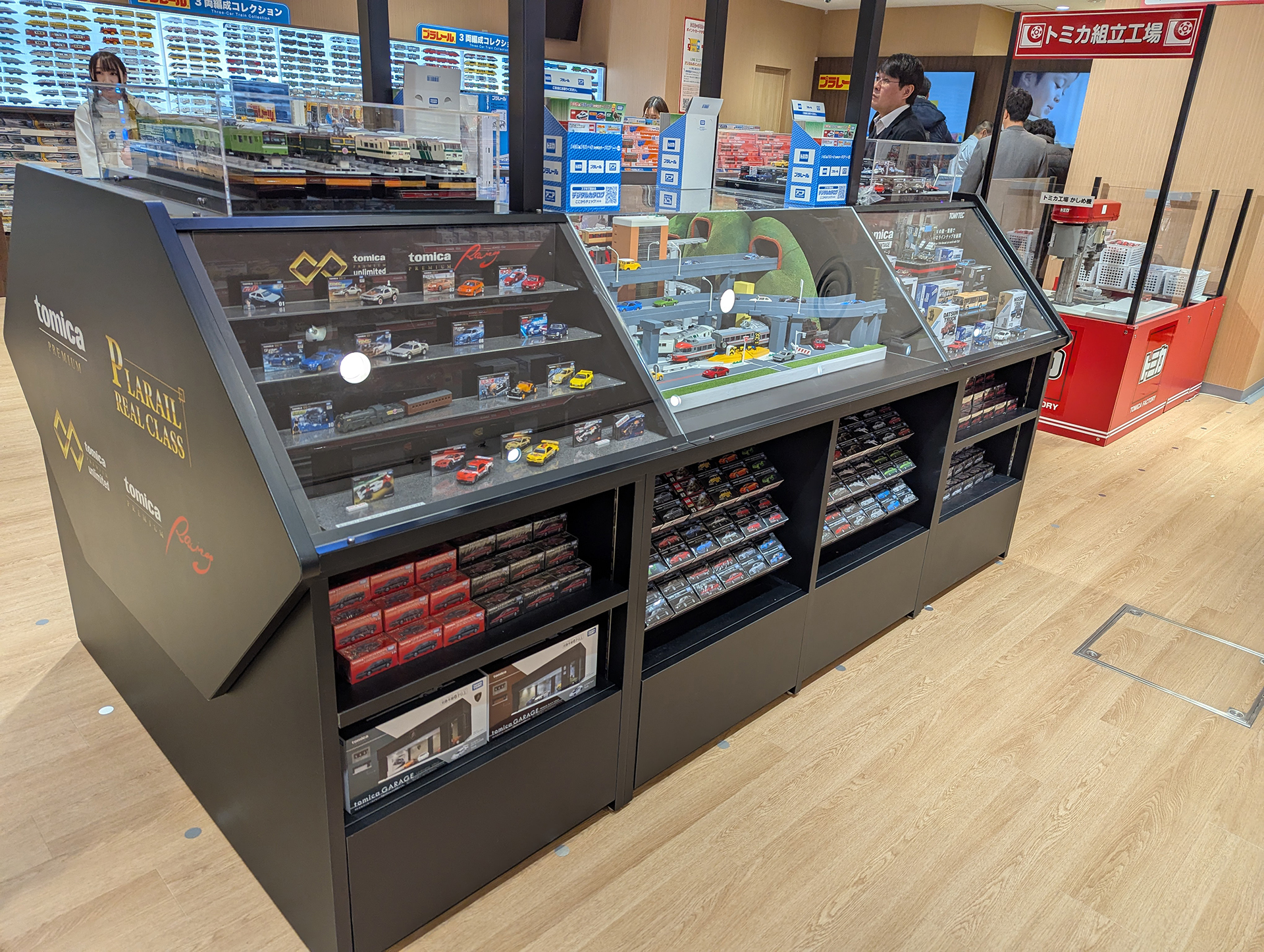 こちらはトミカサイド。ガラスケース内にはシンプルに商品を展示しているほか、ジオラマと絡めた展示もある