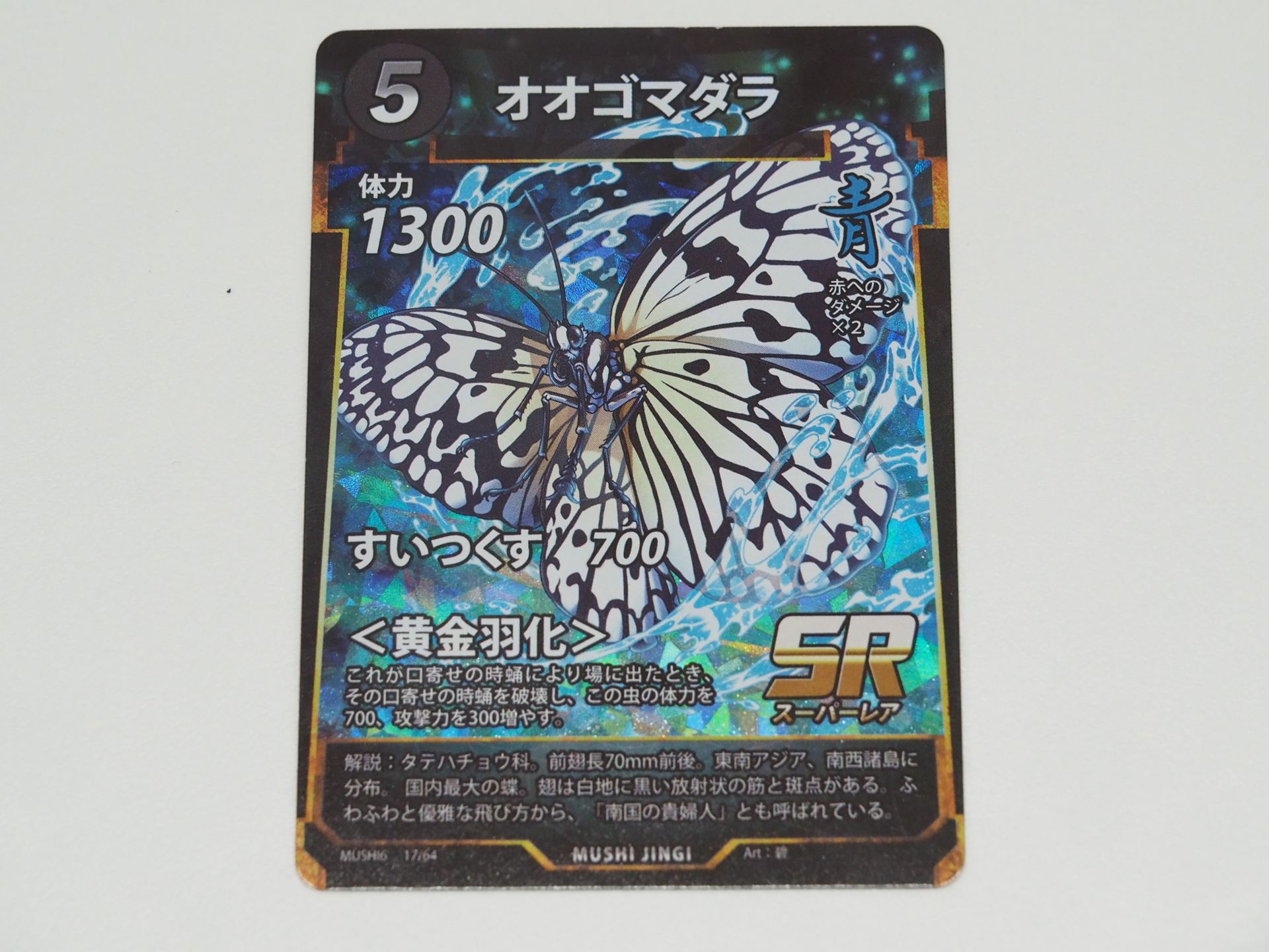 青5コストのSRカード「オオゴマダラ」。先行体験会で初出のカード。口寄せの時蛹により場に出たら、その口寄せの時蛹を破壊し、体力を700、攻撃力を300増やす＜黄金羽化＞を持つ