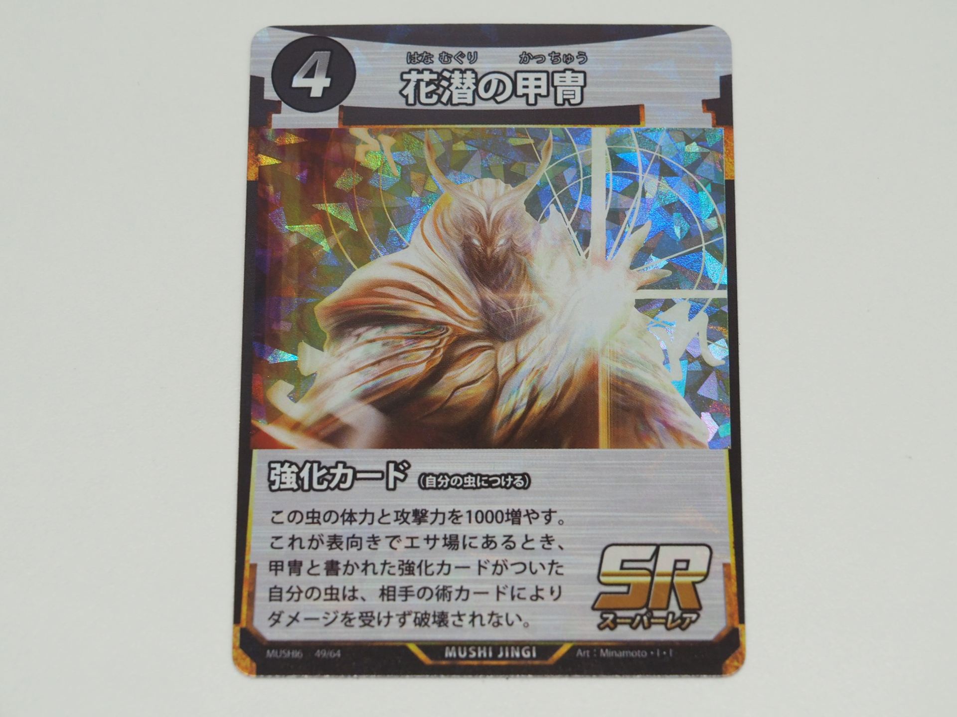 4コストのSR術カード「花潜の甲冑」。付けた虫の体力と攻撃力を1000増やす。さらにこのカードが表向きでエサ場にあれば、甲冑と書かれた強化カードが付いた自分の虫は相手の術カードによりダメージを受けず、破壊もされない