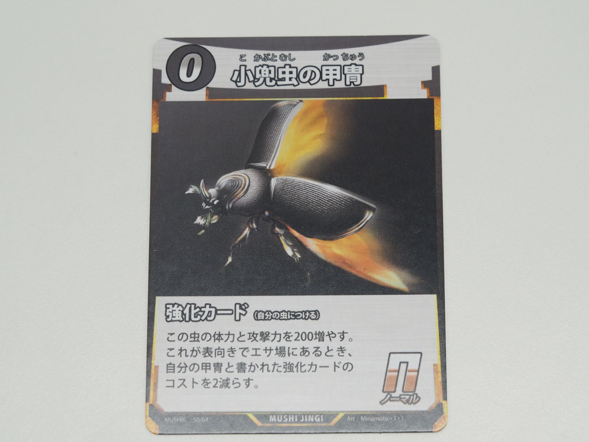 0コストのN強化カード「小兜虫の甲冑」。先行体験会で初出のカード。付けた虫の体力と攻撃力を200増やす。さらにこのカードが表向きでエサ場にあれば、甲冑と書かれた強化カードのコストを2減らす