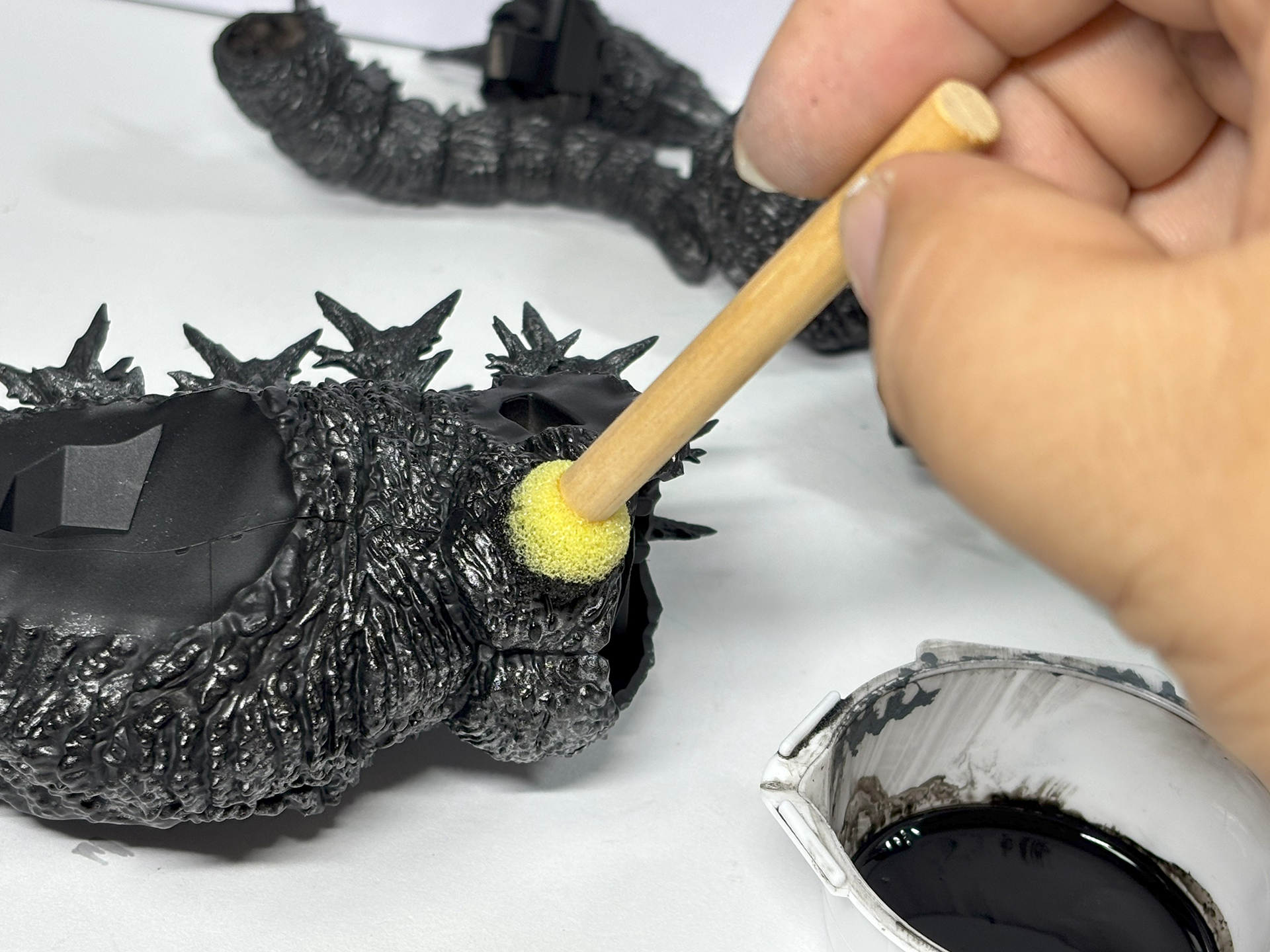 スポンジに塗料をつけてからキッチンペーパーに押しつけ塗料をカスカスになるまで減らした上で、プラモデルの体表に押しつけていく