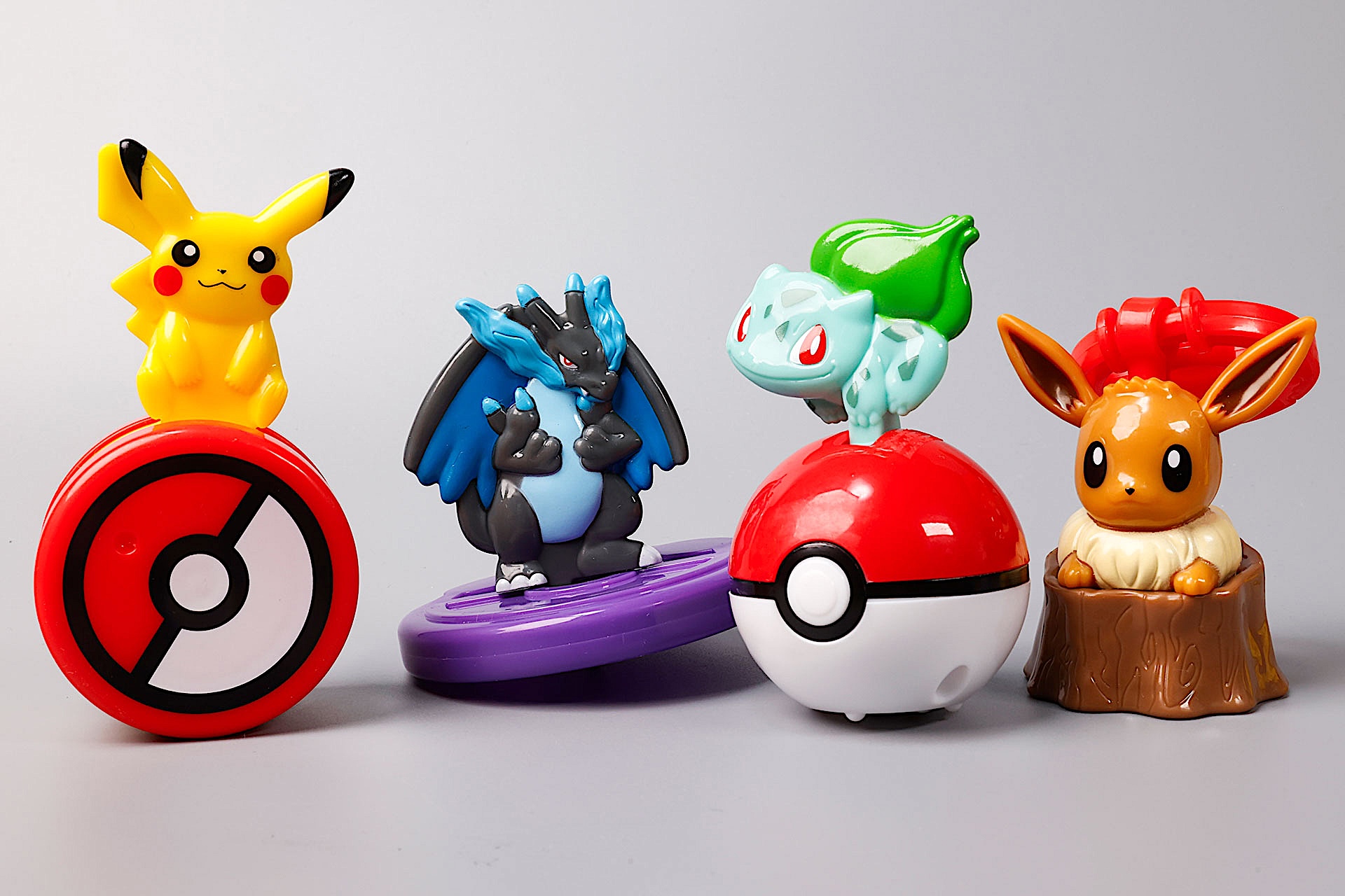 こちらが第2弾(8月15日〜8月21日)のハッピーセット「ポケモン」に登場するおもちゃ。写真左から「ピカチュウのモンスターボールゆらゆらローラー」、「メガリザードンXのくるくるスピナー」、「フシギダネのモンスターボールローラー」、「イーブイ(メス)のシャカシャカキーホルダー」