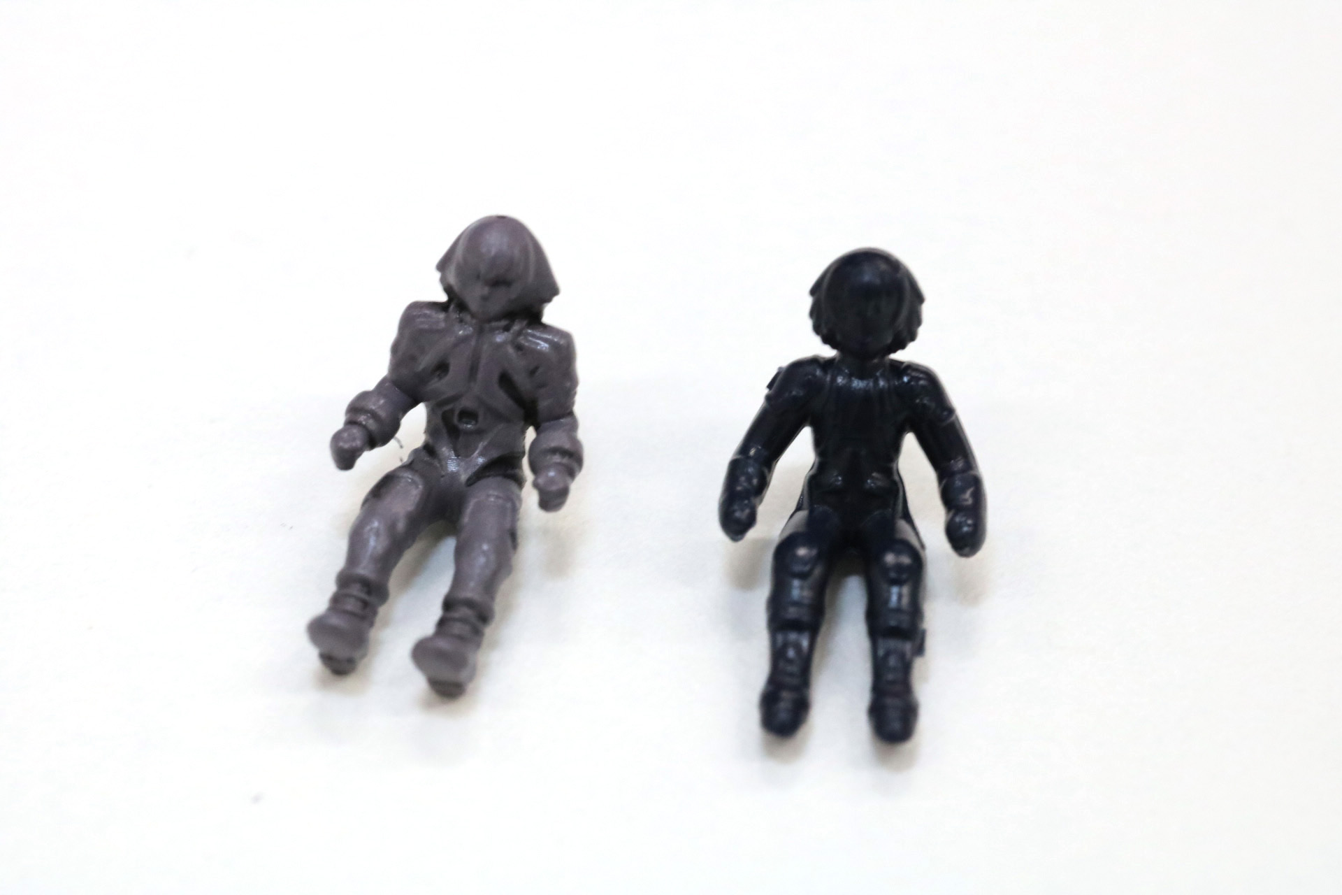 レイヴンのパイロットフィギュアを比較。「AZ-12 ジェノブレイカー」ではGF編のレイヴン（左）、「AZ-09 ジェノザウラー」では少年編のレイヴン（右）が再現されている。