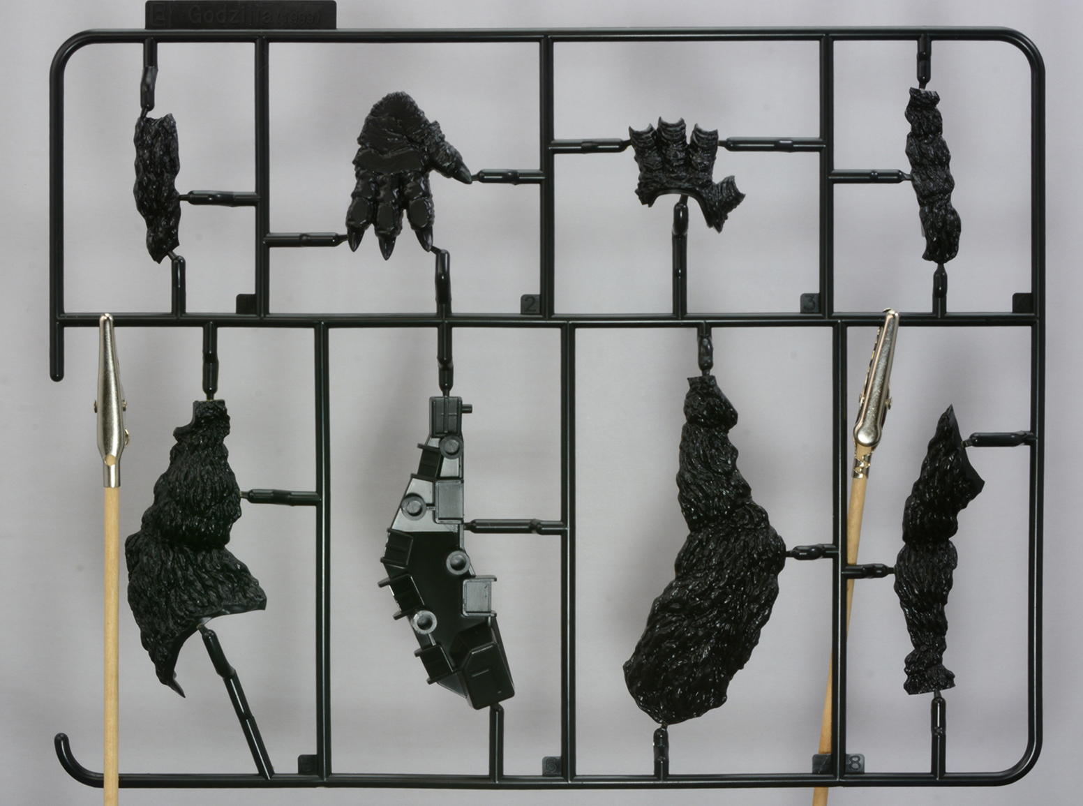 「PLAfig. ゴジラ (1999)」のランナーの一部。ゴジラの生物的な造形をプラモデルパーツで表現。成形色が黒なのもうれしいところだ