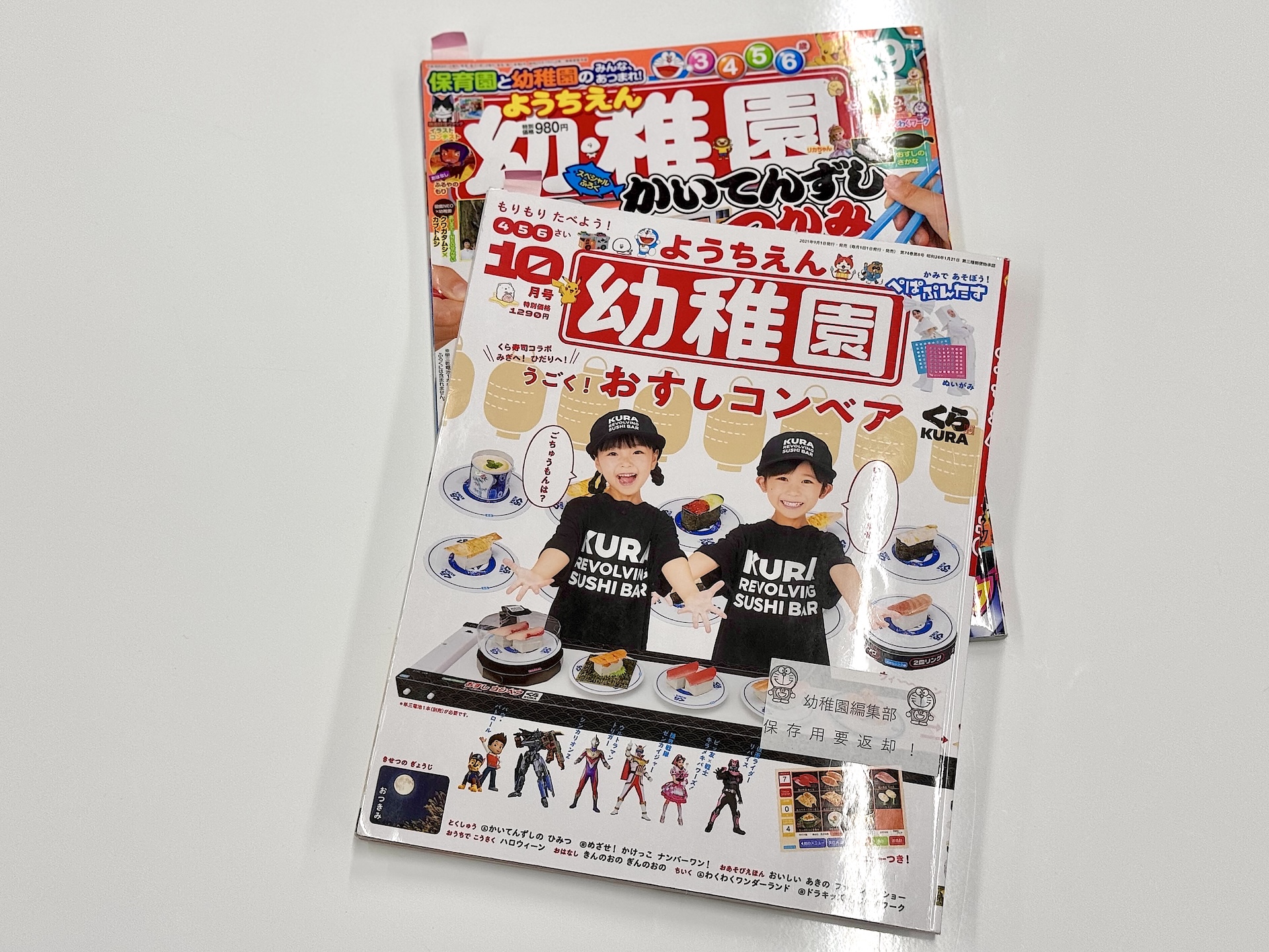 こちらは過去のくら寿司コラボが登場した雑誌。2018年の1回目コラボでは今回と同じく回転ずしをつかむゲームが、2021年の2回目コラボでは動くおすしコンベアが登場。2回目のコラボ時点で「こうきんすしカバー」の再現が登場していた
