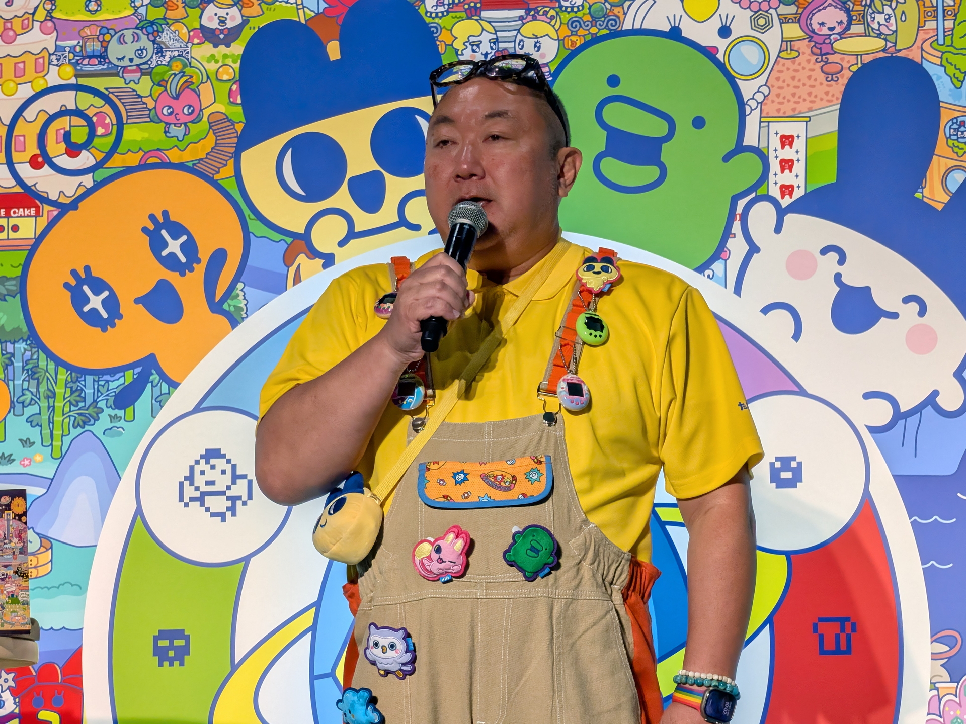 バンダイ 常務取締役、チーフたまごっちオフィサーの辻太郎氏は「たまごっち」があしらわれたつなぎと黄色のTシャツで登壇