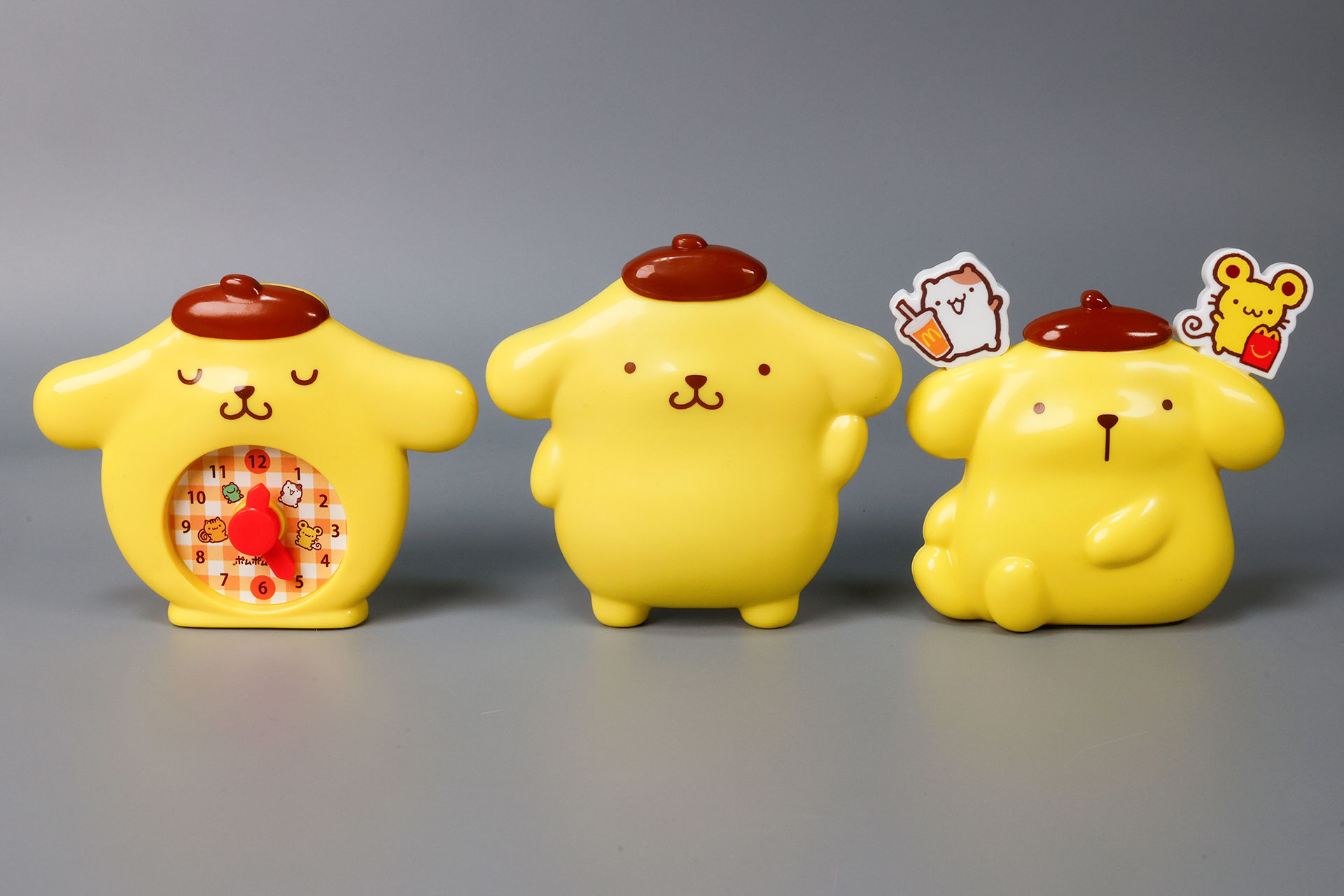 こちらが第2弾（1月23日〜1月29日）のハッピーセット「ポムポムプリン」に登場するおもちゃ。写真左から「ポムポムプリン とけい型 メモスタンド」、「ポムポムプリン ベレー帽 じょうぎ」、「ポムポムプリン なかよしフォークスタンド」