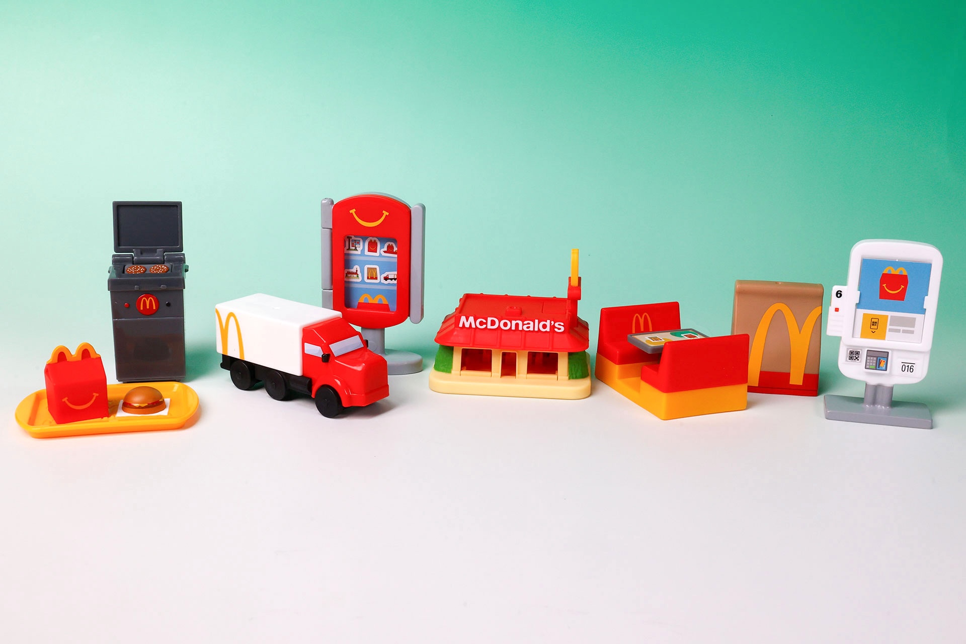 こちらが第1弾（2月27日〜3月5日）のハッピーセット「ミニチュアマクドナルド」に登場するおもちゃ。写真左から「ハッピーセット ハンバーガー＆ハッピーボックス」、「マクドナルド バーガーグリル」、「マクドナルド トラック」、「ハッピーセット おもちゃディスプレイ」、「マクドナルドのおみせ」、「マクドナルド テーブルブース」、「マクドナルドバッグ」、「マクドナルド タッチパネル」