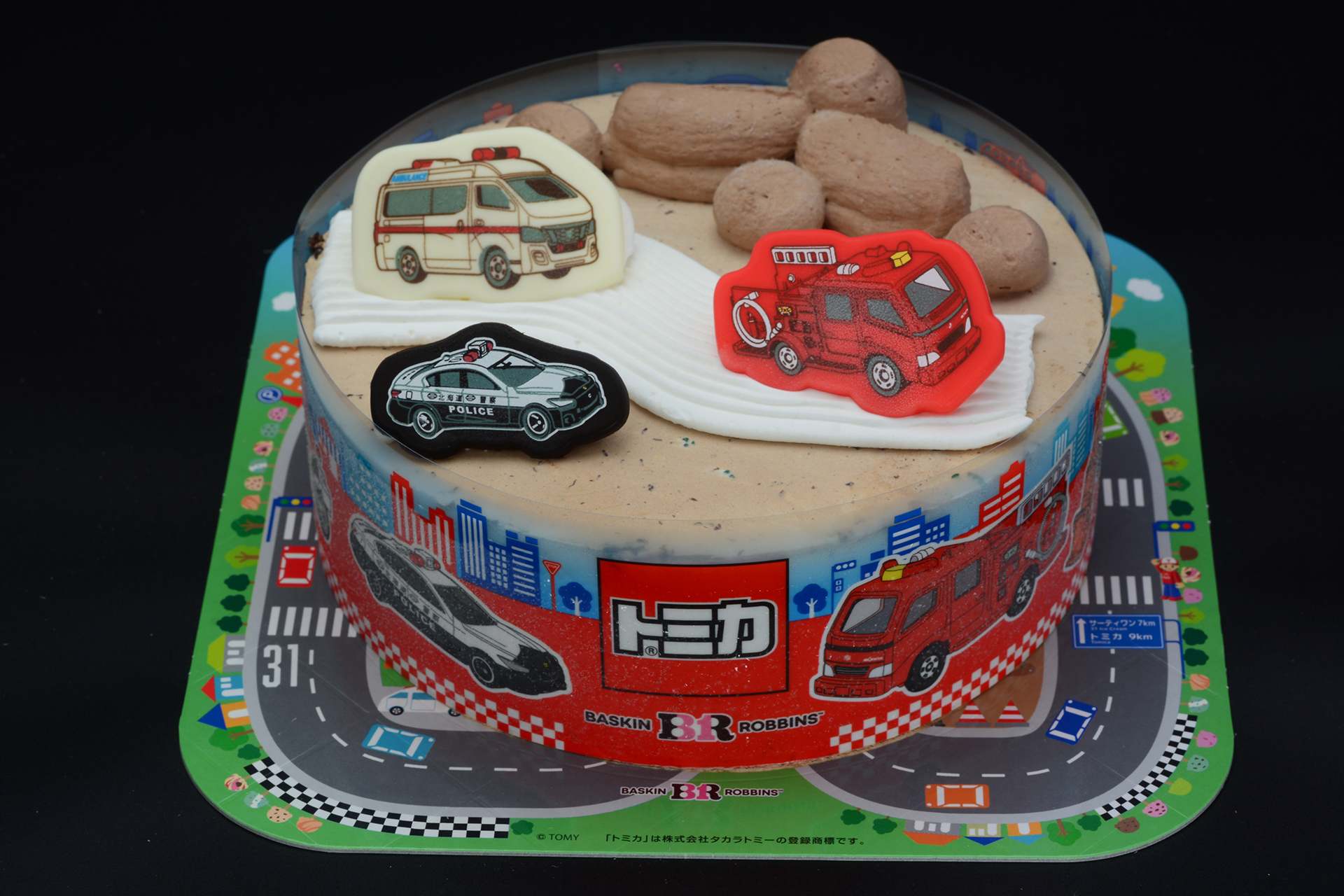 チップドチョコレートに覆われたケーキ。中央に道路を模した白いラインが引かれ、チョコレートプレートに描かれた車が配置されている