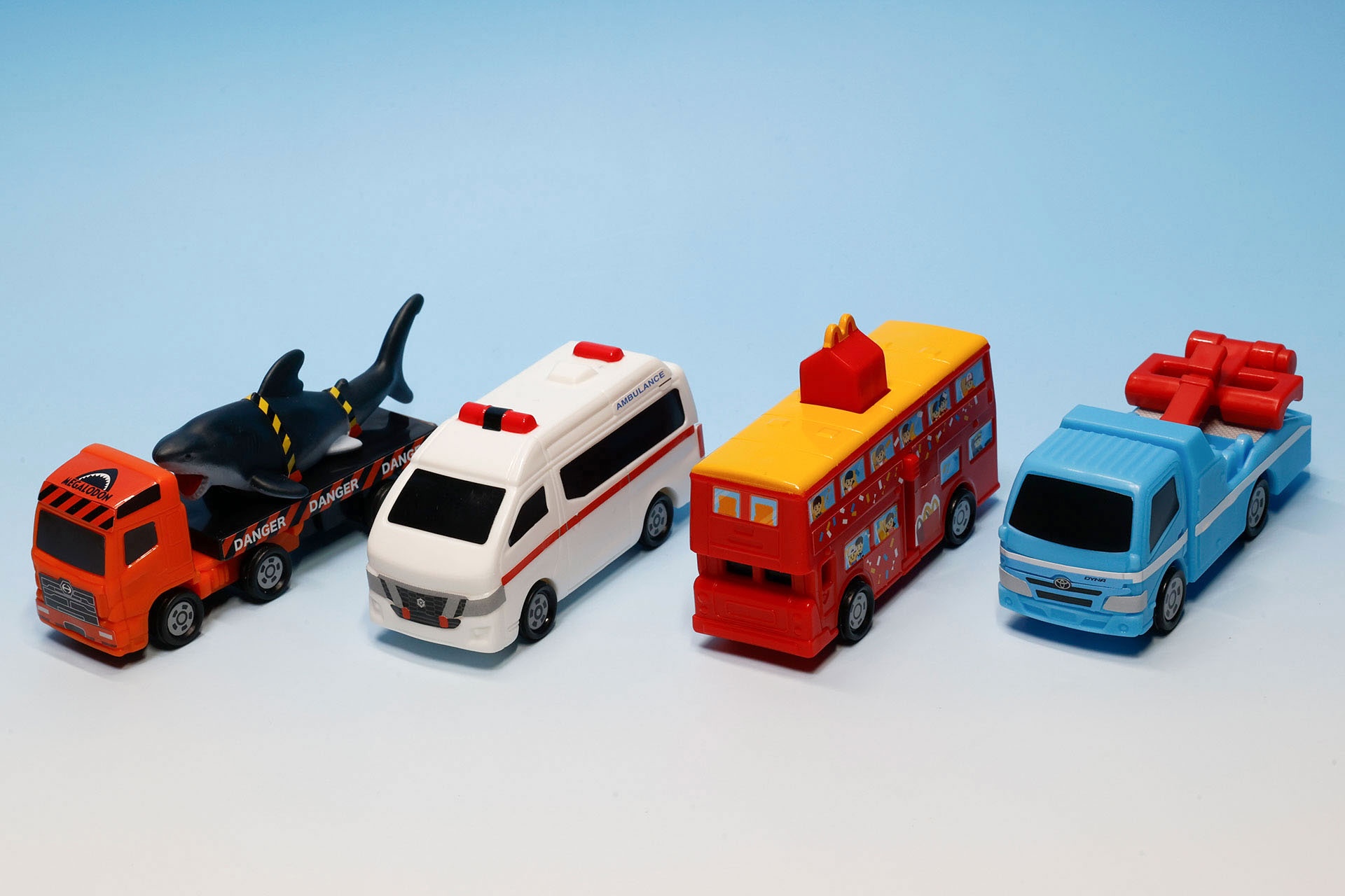 こちらが第2弾（4月24日〜5月7日）のハッピーセット「トミカ」に登場するおもちゃ。写真左から「日野プロフィア メガロドン搬送車」、「日産 NV350 キャラバン 救急車」、「マクドナルド ハッピーセットバス」、「トヨタ ダイナ レッカー車」