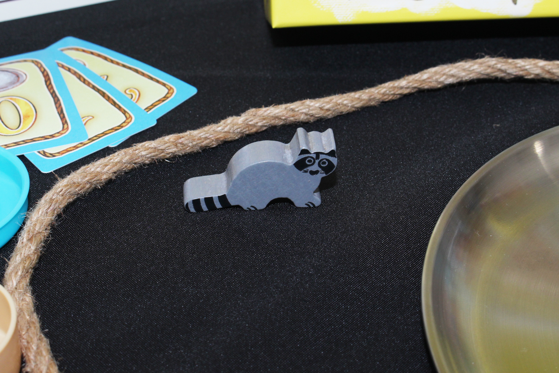 アライグマはゲームのラッキーパーソン。手元にいるときは手番プレイヤーが金を3個取ったときに1個をもらえる。最初は最年長のプレイヤーに渡され、グレーのボールを引いたのもとに移動していく