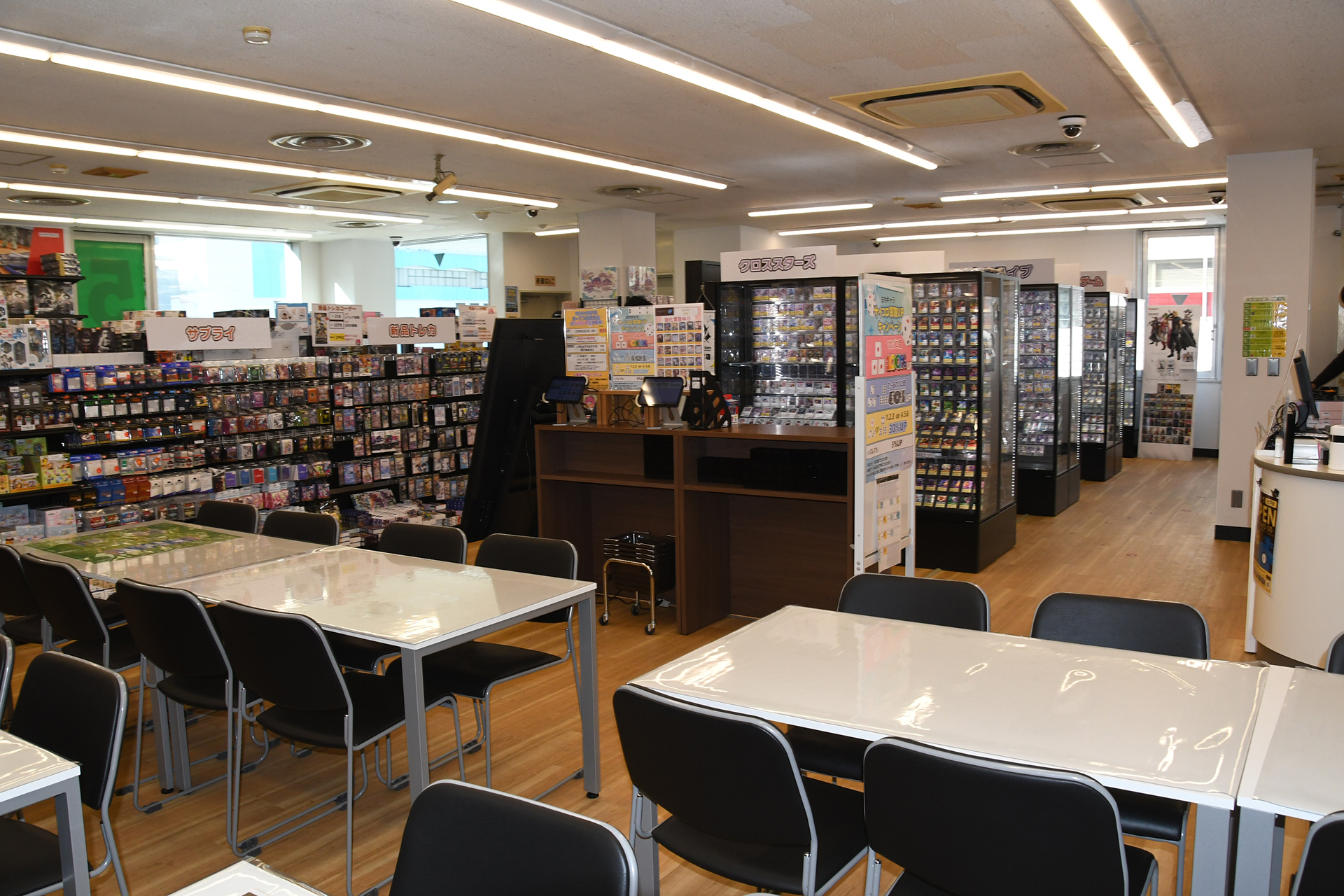 ガラスケースに包まれたトレーディングカードコーナーと、手前の対戦台。「まちキャラ松戸店」は明るく入りやすい店内を意識したレイアウトを意識しているという