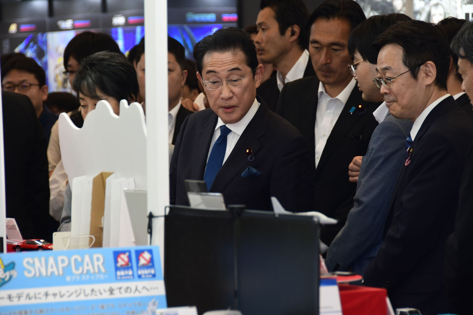 アオシマのブース、「楽プラ」コーナーを視察する岸田元首相と、上川議員
