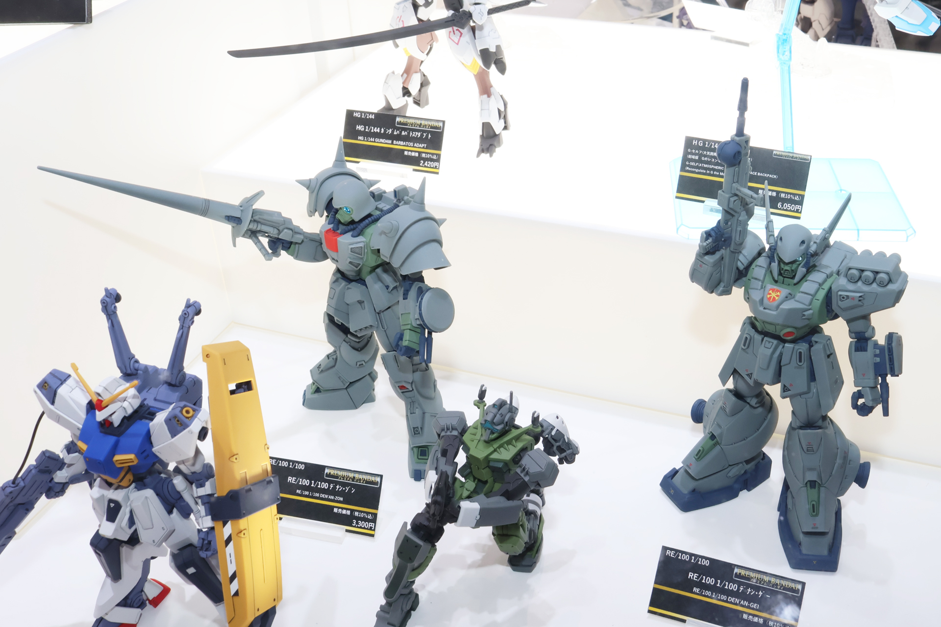 発売済みの「RE/100 1/100 デナン・ゲー」（右）との比較。また周囲の1/144スケールキットとの対比も見ていただきたいところ