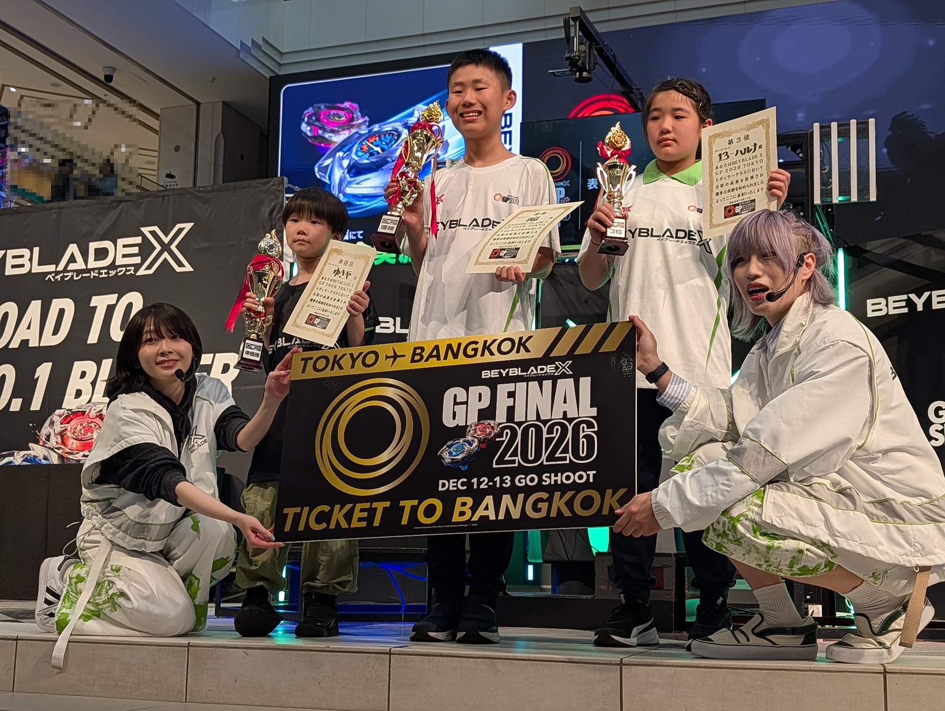 表彰式の3人とMCの2人による記念撮影の様子