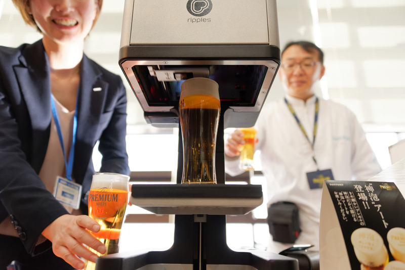 台座に置いたビールグラスが持ち上がり、泡アートが一瞬で描かれる