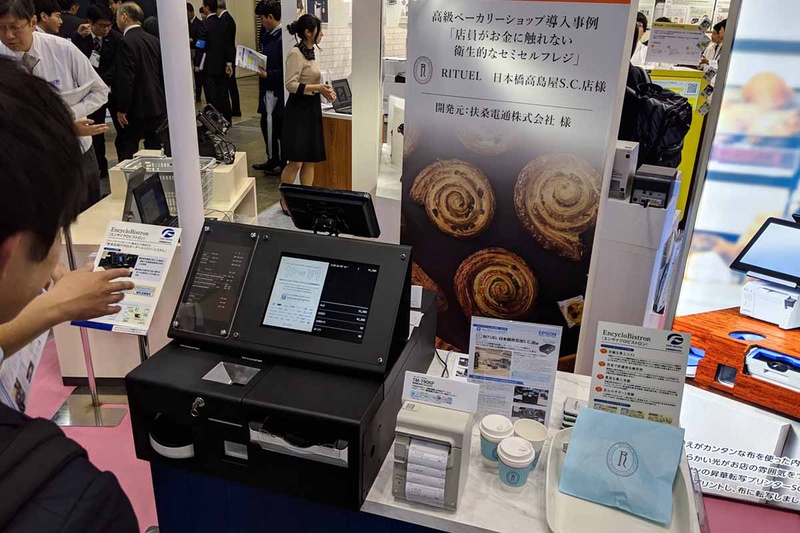 エプソンのブースでは業態ごとにセミセルフの利用提案を行なっていた。パン屋向けは店員が不潔な現金に触れないことを目的としている