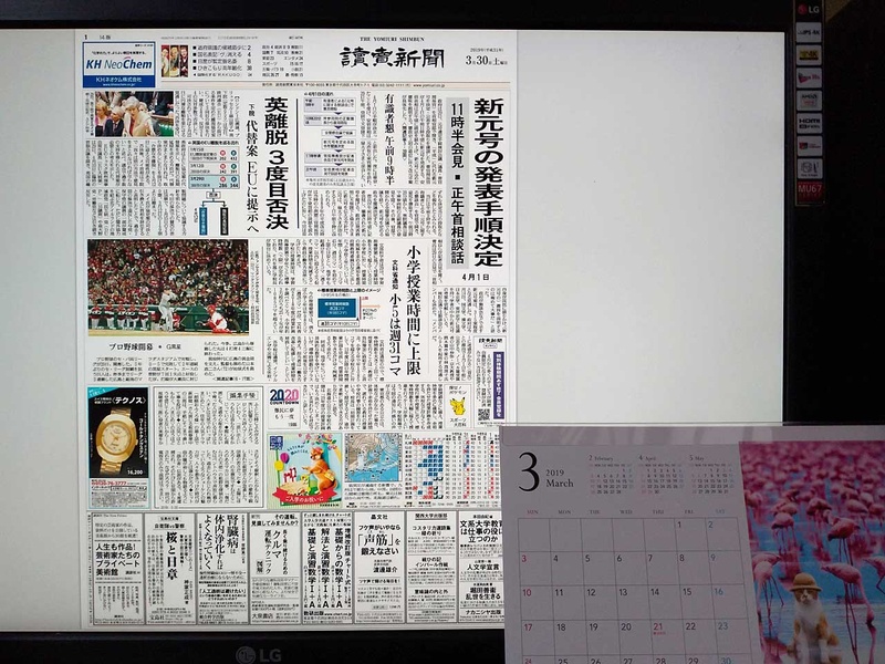 27インチのPCモニター(横配置)で、読売の紙面ビューアーを表示。一般的な卓上カレンダー(右下)と文字サイスを比べてみてほしい