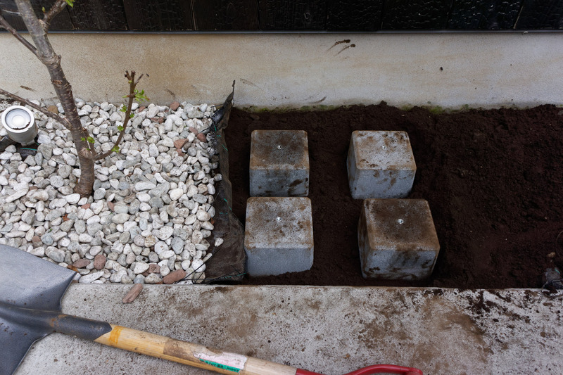 砂利をよけ、土を掘って万能ウエイトを埋設。雨天時に水没しない高さにすることも重要だ