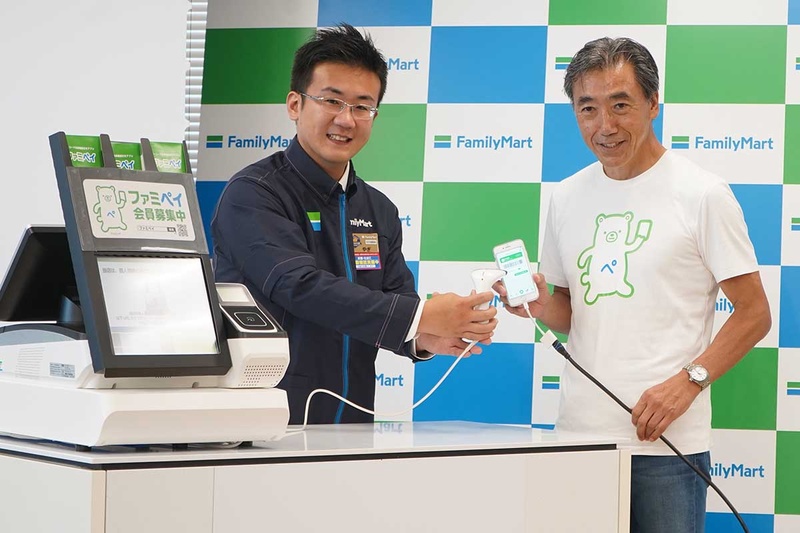 ファミペイを使うファミリーマート澤田社長(右)