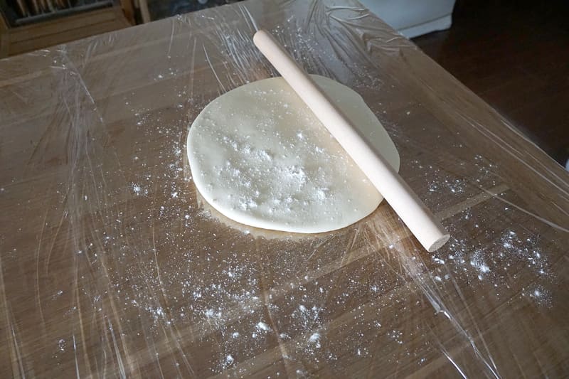 生地を踏み広げるとこんな感じ。めん棒が36cmなので、おそらく直径20cmから25cmぐらい。打ち粉をしてめん棒で伸ばしていく