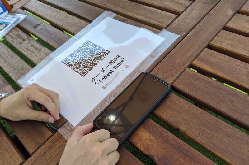 今回の実証実験では芝生に設置された2つのテーブルでのデリバリー注文が可能で、スマートフォンからテーブルのQRコードを読むことでオーダーが出せる