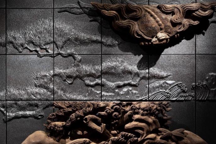 再建前の浄教寺で使用されていた装飾を陶器のレリーフ(制作：陶額堂)と組み合わせ、壁画アートとして構成したもの(1階レセプション)