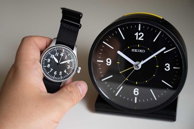 セイコーの電波修正機能対応の目覚まし時計「KR328K」(右)。日常での利用のほか、機械式腕時計(左)の時刻合わせにも最適だ