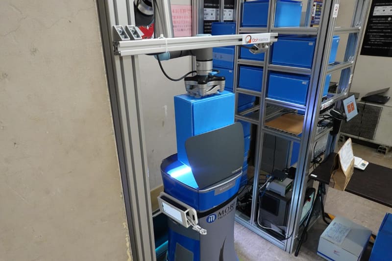 ロボットアームが荷物を取り出し、別のロボットに搭載する