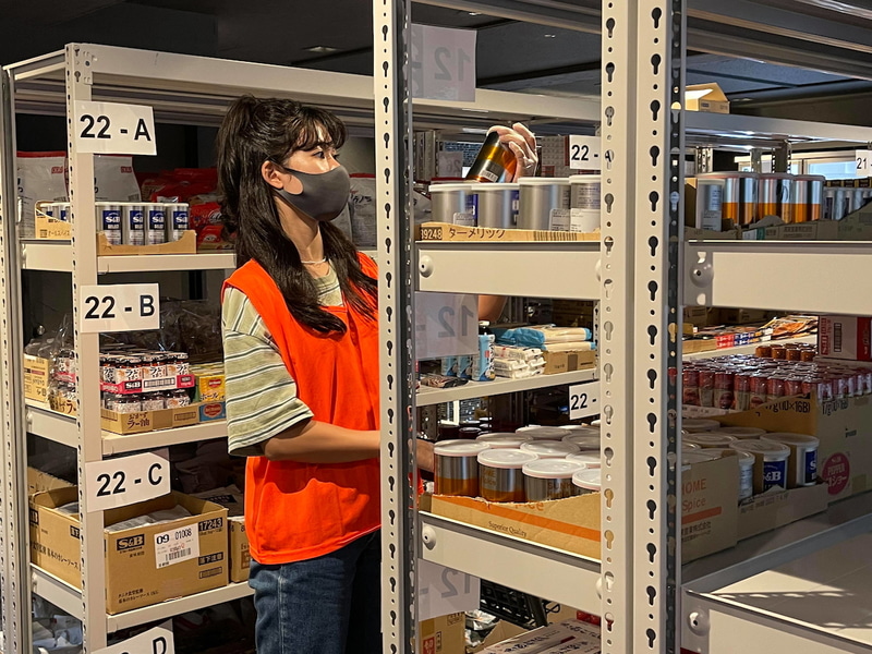 宅配専門のため店舗内は倉庫のように商品が並ぶ。左はピックアップ専門の店員