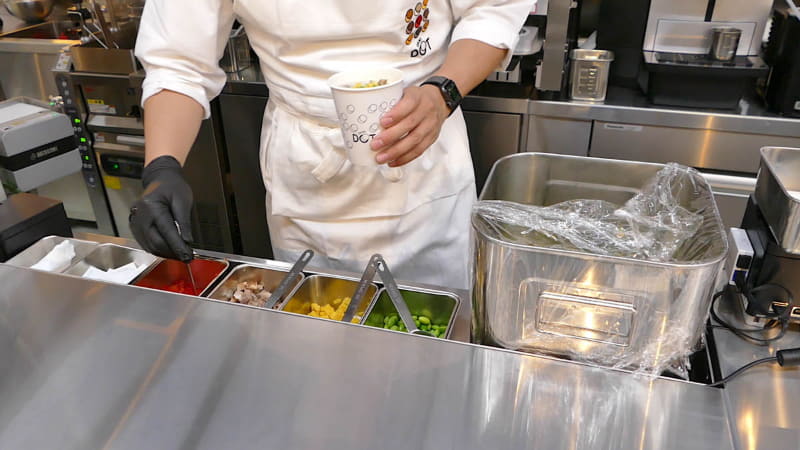 具材のトッピングは人が行なう