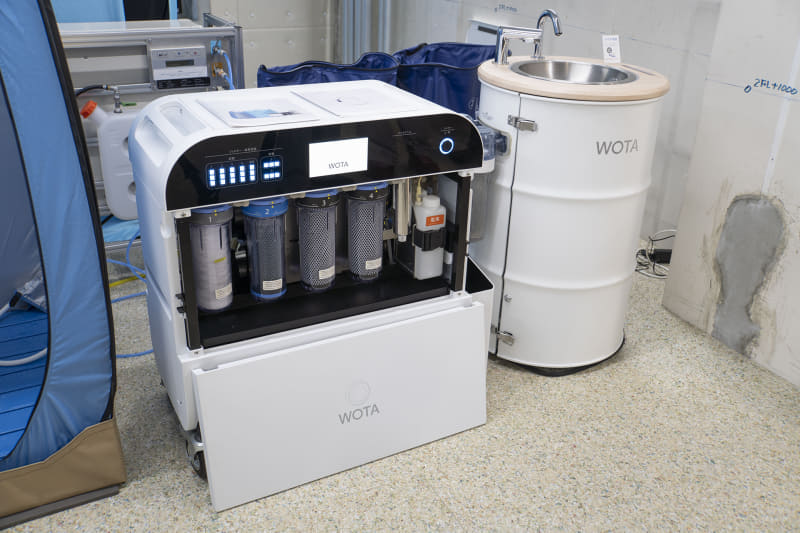 自然の中や災害時など水道のない場所でもシャワーや手洗いができるポータブル水再生システム「WOTA BOX」(左)と、自治体や施設などで設置されている水循環型手洗いスタンド「WOSH」。なお、実証実験で使用されるシステムとは異なる