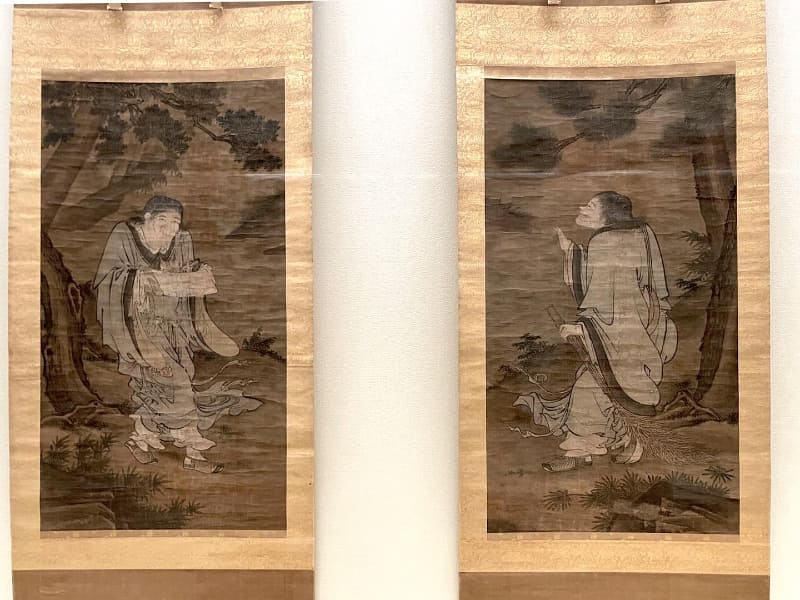中国の明の時代に劉俊(りょうしゅん)によって描かれたとされる《寒山拾得図(寒山拾得蝦蟇鉄拐図のうち)》。写真左の巻物を持っているのが寒山で、同右の箒を持っているのが拾得(本館2階の特集の展示風景)