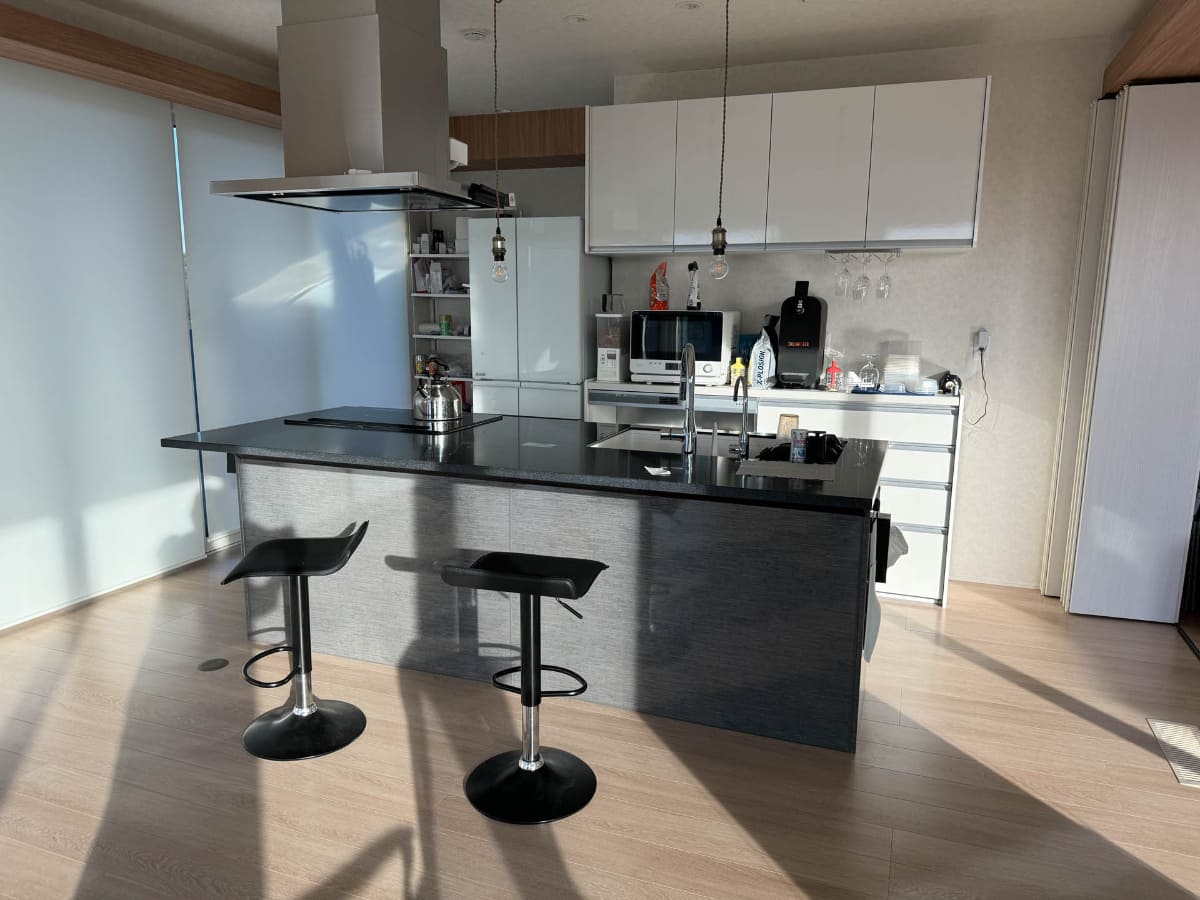 黒系のキッチン本体がトレーシアで、後ろの白いキャビネットはLIXILのアレスタ。冷蔵庫や電子レンジも白系で統一するために地味に手間とコストをかけている