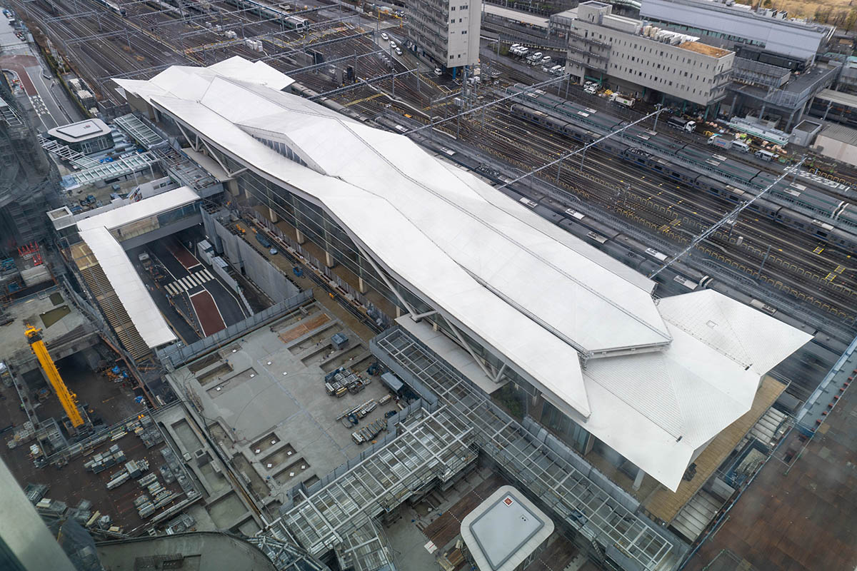 SOUTHの14階から見た高輪ゲートウェイ駅。奥のデッキ(白い屋根)部分が既存の改札、手前側の鉄骨が組まれている部分が新改札