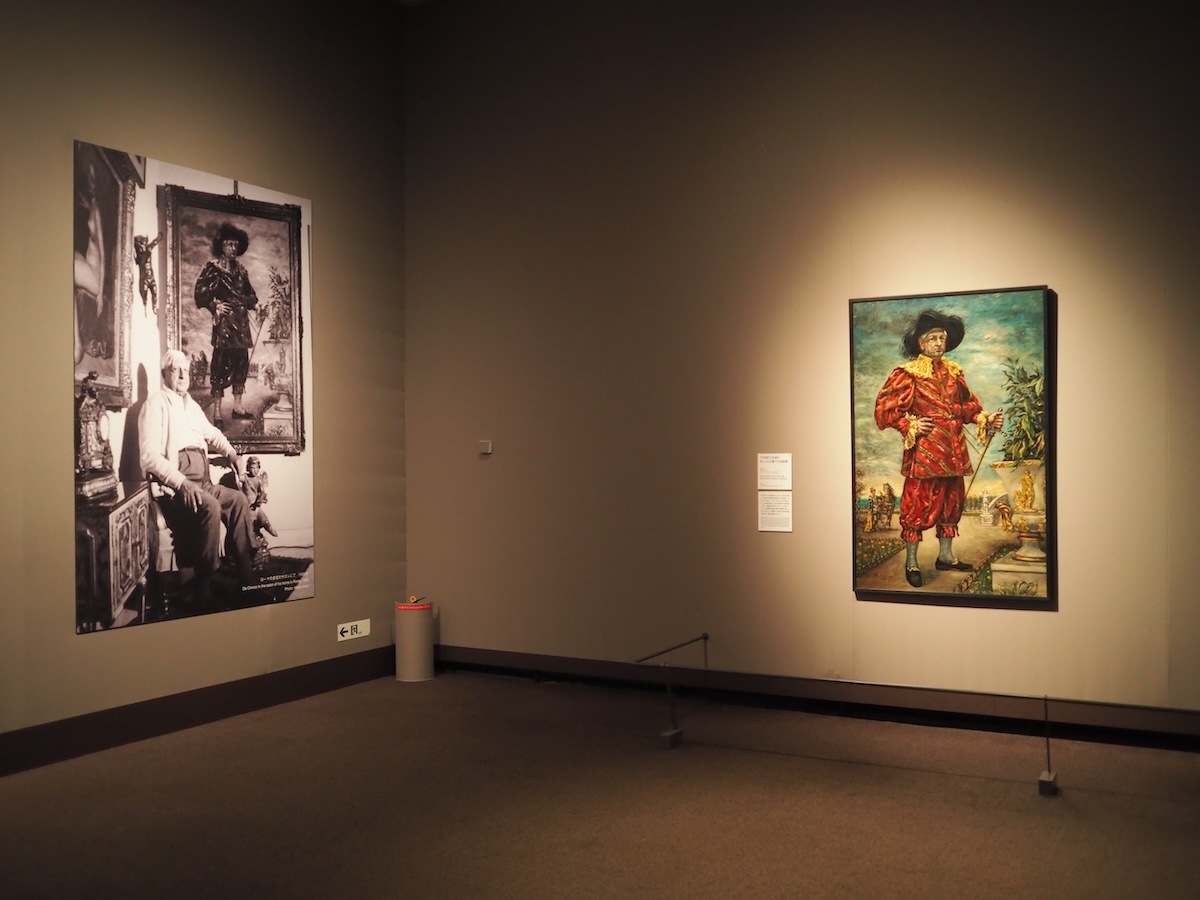 展示風景。ジョルジュ・デ・キリコが1959年に自身を描いた《17世紀の衣装をまとった公園での肖像画》 (C)Fondazione Giorgio e Isa de Chirico, Roma