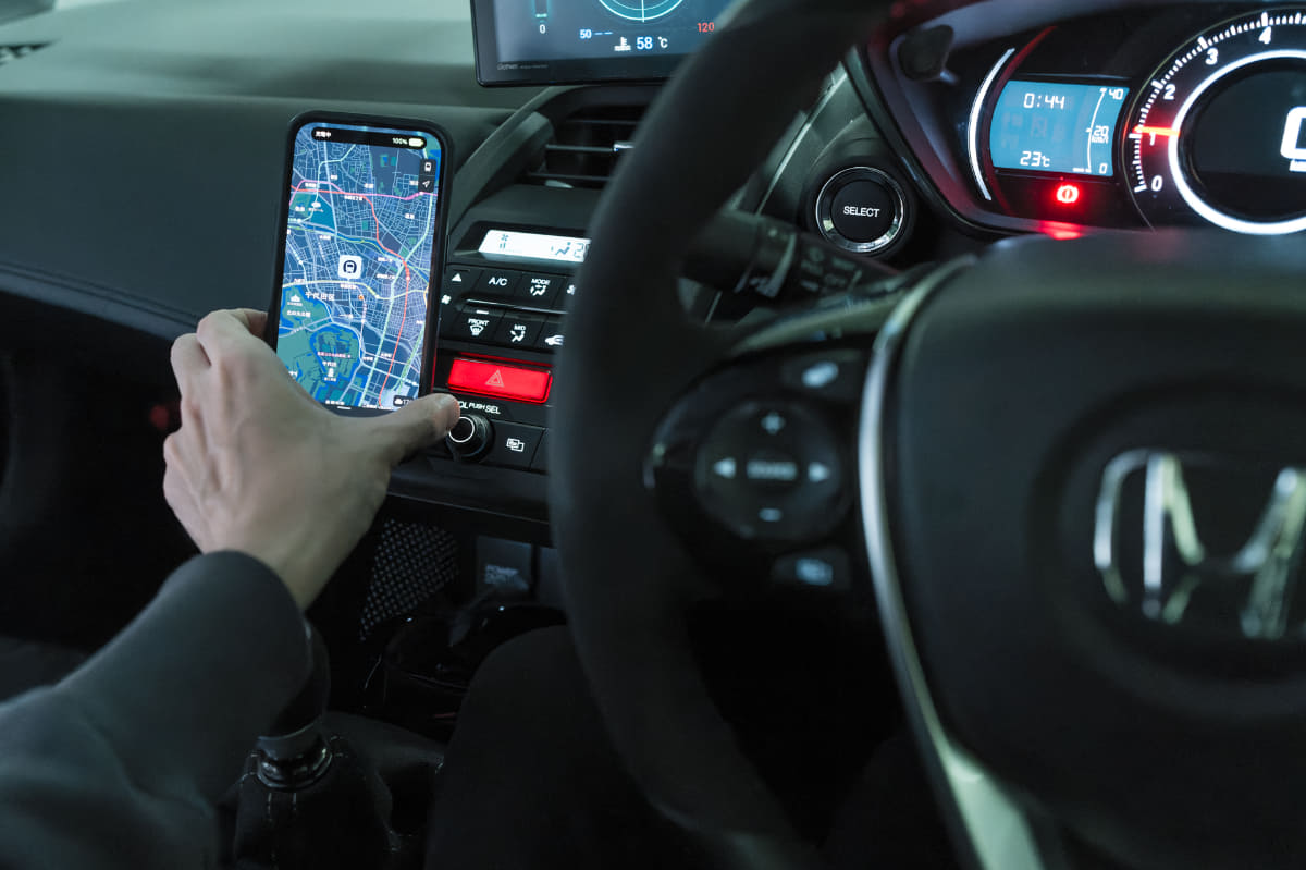 マグネット式のスマホホルダーをクルマに装着。iPhoneを片手でペタッと取り付けると、好みのアングルで保持され、充電も開始されます。降りるときも片手で外せます