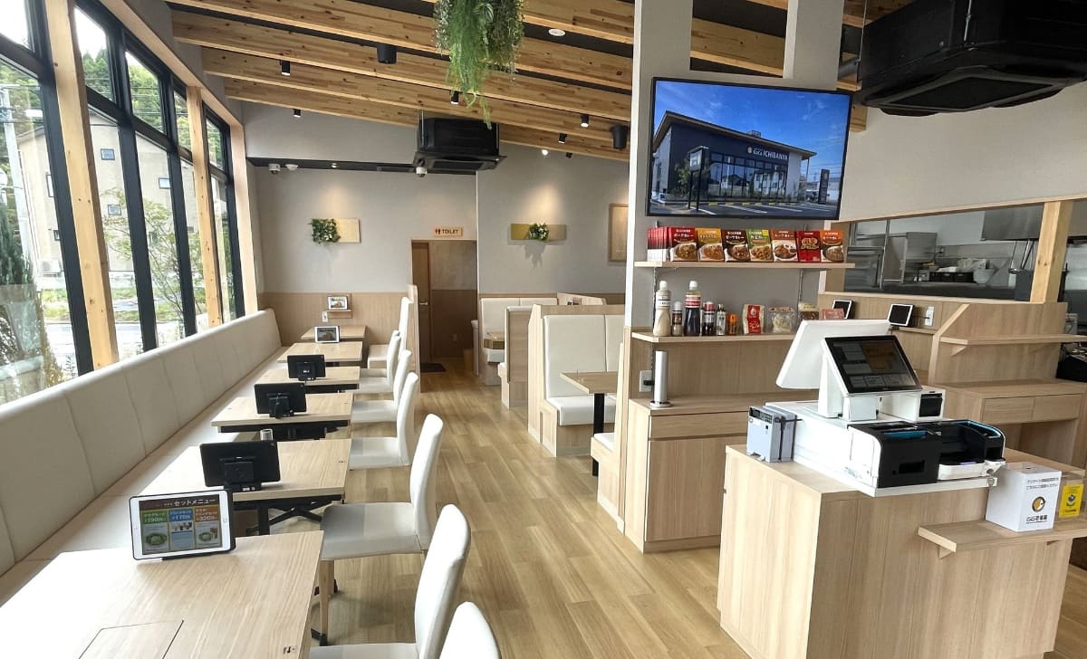 カレーハウスCoCo壱番屋 金沢小坂店の店内。木材の梁を生かし、木目を基調とした内装デザイン。テーブルや椅子はFSC認証家具を採用する