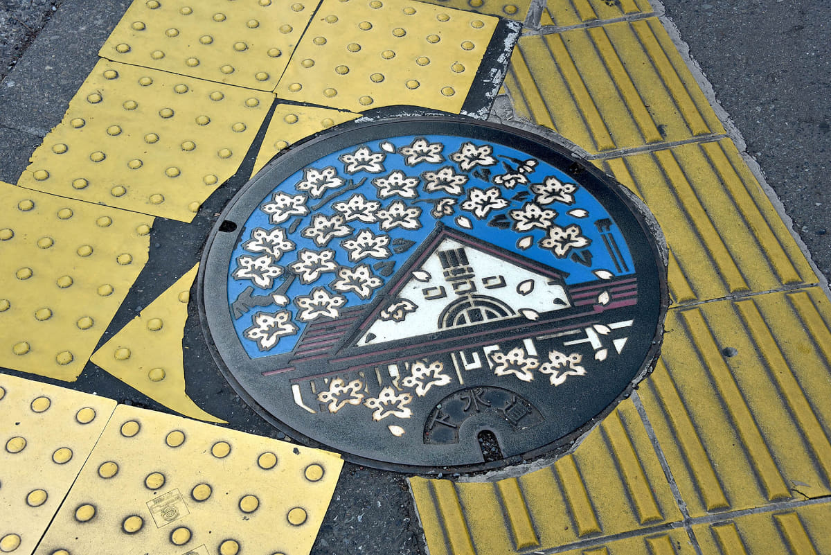 旧駅舎の周囲には、三角屋根の旧国立駅舎をモチーフにしたマンホールがある