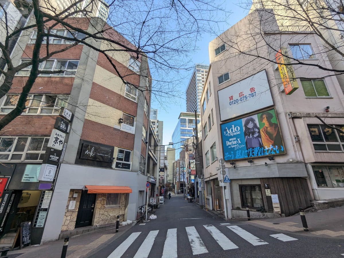 さくら坂の途中で東側の路地をみると、古めの建物の間に今回の再開発でできた「ブランズ渋谷桜丘」および「ハイアットハウス東京渋谷」が入るSAKURAタワーB棟が見えます